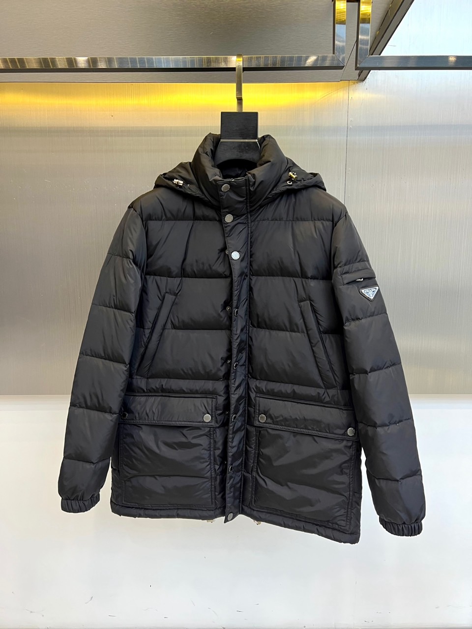 NO:608670,Prad, the new 2025 autumn and winter down jacket, uses classic black to interpret Italian functional aesthetics. This hooded down jacket uses three-dimensional diamond quilting technology, and its regular geometric outline enhances thermal insulation performance while avoiding a bloated feeling. The multi-pocket design uses an asymmetric layout to create practicality and visual hierarchy, and the metal grommets and zipper accessories highlight exquisite details. The fabric is made of high-tech windproof material, and is filled with high-quality down to ensure light warmth. Its design provides outdoor protection  Perfectly integrated with urban fashion, the neat tailoring adapts to a variety of body shapes. It can be paired with formal wear to create a business casual look, or combined with sportswear to show a trendy attitude. From urban commuting to suburban travel, this down jacket uses Prada's unique minimalist aesthetics and pragmatism to become a smart choice for autumn and winter that combines luxury texture and functionality. 48-56 (model is 173,143 pounds, upper body size 50),, prada, prada, down  jacket,hats,alexander wang19860909Prad普拉达、2025秋冬新款羽绒服以经典黑色演绎意式功能美学.这款连帽羽绒服采用立体菱形绗缝工艺,规整的几何轮廓增强保暖性能的同时避免臃肿感.多口袋设计以不对称布局打造实用性与视觉层次,金属扣眼与拉链配件彰显精致细节.面料选用高科技防风材质,填充优质羽绒确保轻盈保暖性.其设计将户外防护与都市时尚完美融合,利落剪裁适配多种身形,既可搭配正装打造商务休闲造型,也能结合运动服饰展现潮流态度.从城市通勤到近郊出行,这件羽绒服以普拉达特有的极简美学与实用主义,成为秋冬季节兼具奢华质感与功能性的智慧之选.48-56（模特173,143斤上身50码）,,prada,prada,down jacket,hats,alexander wang,Men's clothing