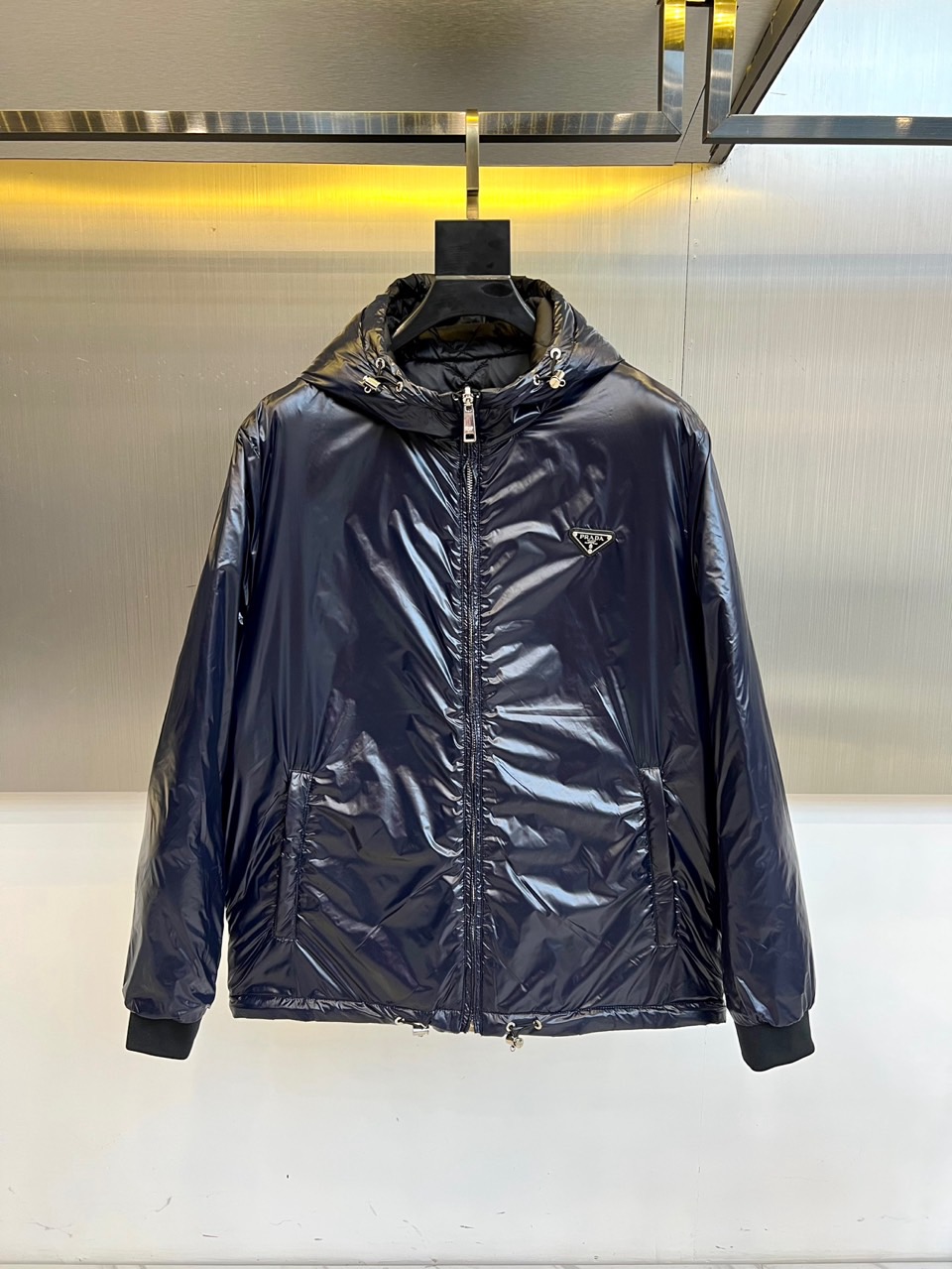 NO:608673,Prada, the 2025 autumn and winter reversible down jacket interprets practical aesthetics with innovative design. The black version uses diamond plaid quilting technology to create a three-dimensional silhouette, a hooded design with a smooth zipper, the iconic triangle logo on the left chest, and knitted ribbing on the cuffs to enhance windproof performance. The dark blue version uses glossy materials to present a modern texture, with metal brim rings and silver zippers to complement each other. Both models are made of environmentally friendly recycled fiber fabrics, filled with 90% high-quality white duck down, and worn on both sides.  Designed to achieve style transformation. Its design perfectly integrates brand genes and outdoor functions. The black side shows classic luxury, while the dark blue side reveals urban fashion. From daily commuting to weekend travel, this down jacket can adapt to different scenes with multiple wearing modes. The exquisite craftsmanship and environmental protection concept in the details highlight Prada’s dual pursuit of quality and sustainable development. 48-56 (model is 173, 143 pounds, upper body size 50),, prada, prada, down  jacket,hats,alexander wang19860909Prad普拉达、2025秋冬双面穿羽绒服以创新设计诠释实用美学.黑色款采用菱形格纹绗缝工艺塑造立体轮廓,连帽设计搭配顺滑拉链,左胸点缀标志性三角徽标,袖口针织罗纹增强防风性能.深蓝色款则以亮面材质呈现现代质感,金属帽檐环饰与银色拉链相映成趣.两款均采用环保再生纤维面料,填充90优质白鸭绒,通过双面穿设计实现风格转换.其设计将品牌基因与户外功能完美融合,黑色面展现经典奢华,深蓝面流露都市时尚.从日常通勤到周末出行,这件羽绒服能以多重穿着模式适应不同场景,细节处的精湛工艺与环保理念,彰显普拉达对品质与可持续发展的双重追求.48-56（模特173,143斤上身50码）,,prada,prada,down jacket,hats,alexander wang,Men's clothing