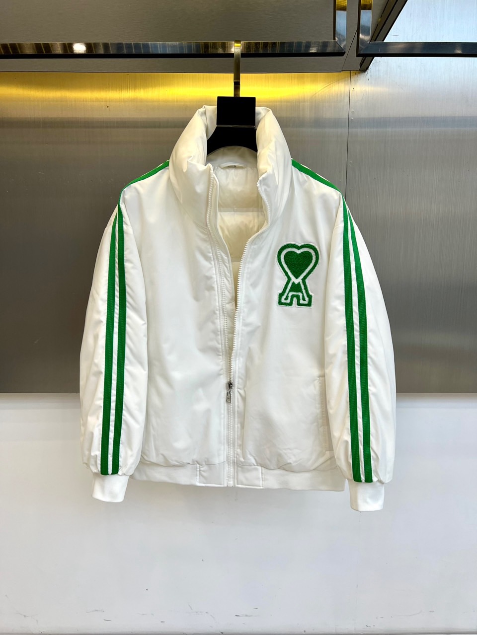 NO:608679,Ami  The new 2025 autumn and winter down jacket combines sports aesthetics with a simple stand-up collar design to redefine urban winter fashion. The style adopts a neat zipper opening and closing design, with the brand's iconic green stripes on the sleeves and highly recognizable green hearts and letters on the left chest.  A' combined embroidery. The fabric is made of polyester fiber, which is light, crisp and windproof; it is filled with 85% high-quality white duck down, and the down content strictly complies with GB/T14272-standard. The filling amount of M size is up to 76 grams, and multiple size gradients ensure a suitable fit.  Its three-dimensional tailoring combines warmth and freedom of movement, and the green stripe details inject vitality into the pure white tone. It can be paired with pants of the same color to enhance the overall look, or it can be combined with jeans to create a mixed style. From city walks to suburban excursions, this down jacket interprets the brand's insight into modern lifestyle with the balance of environmentally friendly materials and practical aesthetics, becoming a must-have item that connects daily commuting and weekend leisure. 48-56 (model is 173,143 pounds, upper body size 50),,jeans,down jacket,alexander  wang19860909Ami 2025秋冬新品羽绒服,以简约立领设计融合运动美学,重新定义都市冬日时尚.款式采用利落的拉链开合设计,袖侧饰有品牌标志性的绿色条纹,左胸点缀辨识度极高的绿色心形与字母'A'组合刺绣.面料选用聚酯纤维材质,轻盈挺括且具备防风性能；填充85高品质白鸭绒,绒子含量严格符合GB/T14272-标准,M码充绒量达76克,多尺码梯度确保合身选择. 其立体剪裁兼顾保暖性与活动自由度,绿色条纹细节为纯白基调注入活力.可搭配同色系裤装强化整体感,亦能与牛仔裤碰撞出混搭风格.从城市漫步到郊外远足,这款羽绒服以环保材质与实用美学的平衡,诠释品牌对现代生活方式的洞察,成为连接日常通勤与周末休闲的必备单品.48-56（模特173,143斤上身50码）,,jeans,down jacket,alexander wang,Men's clothing