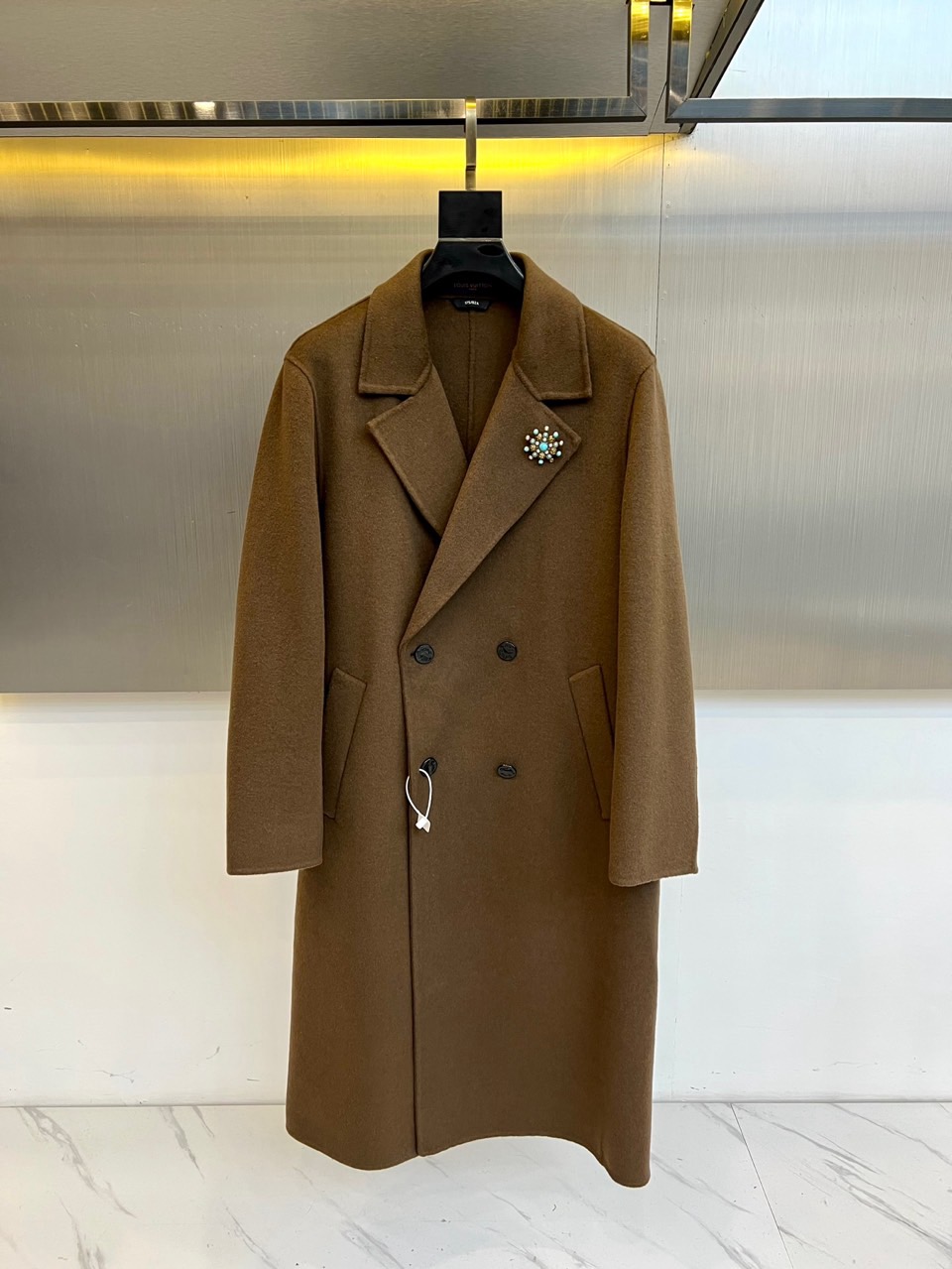 NO:608665,1v Vuitton, the new men's cashmere coat for autumn and winter 2025, interprets timeless classics in deep brown. This double-breasted coat is made of worsted wool blended fabric, containing 68.9 sheep wool and 27.2 polyester fiber, which not only maintains the natural texture of wool, but also gives the fabric good wrinkle resistance. The classic lapel line is neat and smooth, four black buttons are neatly arranged, the left chest is embellished with a metal brooch with the brand logo, and the decorative button details at the cuffs highlight the craftsmanship.  Its tailoring combines modern aesthetics and traditional techniques, with straight and natural shoulder lines and a slightly tapered waist to outline a slender silhouette. The fabric complies with GB18401-2010 Category C safety standards, and the lining is made of smooth material to ensure wearing comfort. The practical pockets on both sides balance function and aesthetics. Whether it is paired with a formal suit to show a business temperament, or paired with a turtleneck sweater to create a casual look, this coat can enhance the overall texture with a calm brown tone.  From important business occasions to evening social events, this coat has become a must-have item for the autumn and winter wardrobe with its exquisite craftsmanship and timeless design. Every detail reflects Louis Vuitton’s pursuit of quality. The precise lapel angle, even and fine stitching, and texture  Outstanding metal accessories. It is not only a warm jacket, but also a statement piece showing French luxury style, allowing the wearer to still maintain elegance in the cold season. 48-56 (model 173, 143 pounds, upper body size 50),, louis  vuitton,jackets & coats,sweaters,brooch,breastpin,alexander wang198609091v威登、2025秋冬新品男士羊绒大衣,以深邃棕色诠释永恒经典.这款双排扣大衣采用精纺羊毛混纺面料,含68.9绵羊毛与27.2聚酯纤维,既保持羊毛的天然质感,又赋予面料良好的抗皱性.经典的翻驳领线条利落流畅,四粒黑色纽扣整齐排列,左胸点缀品牌标识金属胸针,袖口处装饰扣细节彰显匠心工艺. 其剪裁融合现代审美与传统技艺,肩部线条挺拔自然,腰身微收勾勒修长轮廓.面料符合GB18401-2010 C类安全标准,内衬选用顺滑材质确保穿着舒适度.两侧实用口袋兼顾功能与美学平衡,无论是搭配正装展现商务气质,还是配合高领毛衣打造休闲造型,这件大衣都能以沉稳的棕色调提升整体质感. 从重要商务场合到晚间社交活动,这件大衣以其精湛工艺与永恒设计成为秋冬衣橱的必备单品.每一个细节都体现路易威登对品质的追求精准的翻驳领角度、均匀细密的缝线、质感出众的金属配件.它不仅是保暖外套,更是展现法式奢华风格的宣言单品,让穿着者在寒冷季节依然保持优雅风度.48-56（模特173,143斤上身50码）,,louis vuitton,jackets & coats,sweaters,brooch，breastpin,alexander wang,Men's clothing