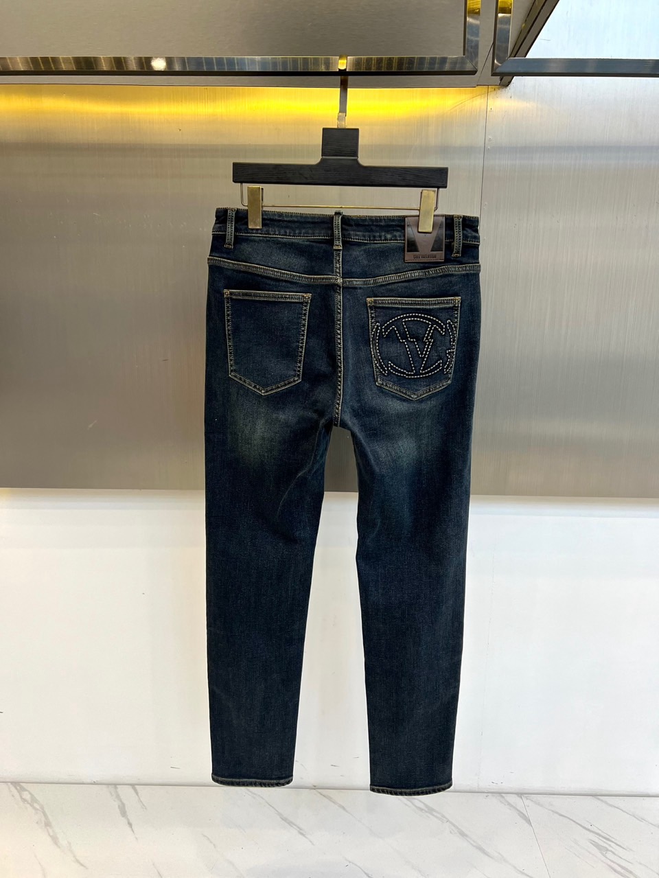 VT华伦天奴、2025秋冬新品深蓝色牛仔裤，采用高密度棉质面料打造挺括且柔软的穿着体验。后袋饰有品牌标志