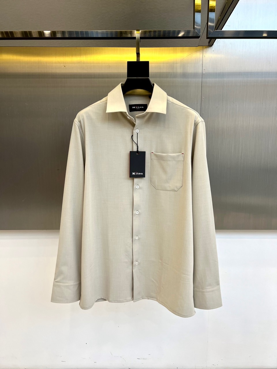 Kiton-2025秋冬新品匠心工艺衬衫。这款卡其色衬衫采用经典翻领设计，前襟搭配五颗天然母贝纽扣，左胸