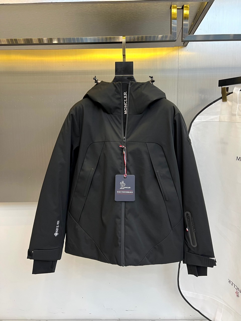 MON蒙口（高端鹅绒）、2025秋冬新品男士连帽羽绒外套，色调演绎现代户外机能风格。连帽设计搭配红白蓝三