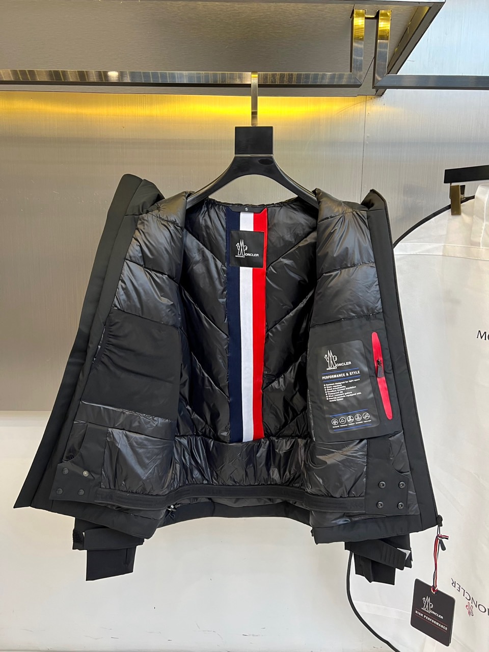 MON蒙口（高端鹅绒）、2025秋冬新品男士连帽羽绒外套，色调演绎现代户外机能风格。连帽设计搭配红白蓝三