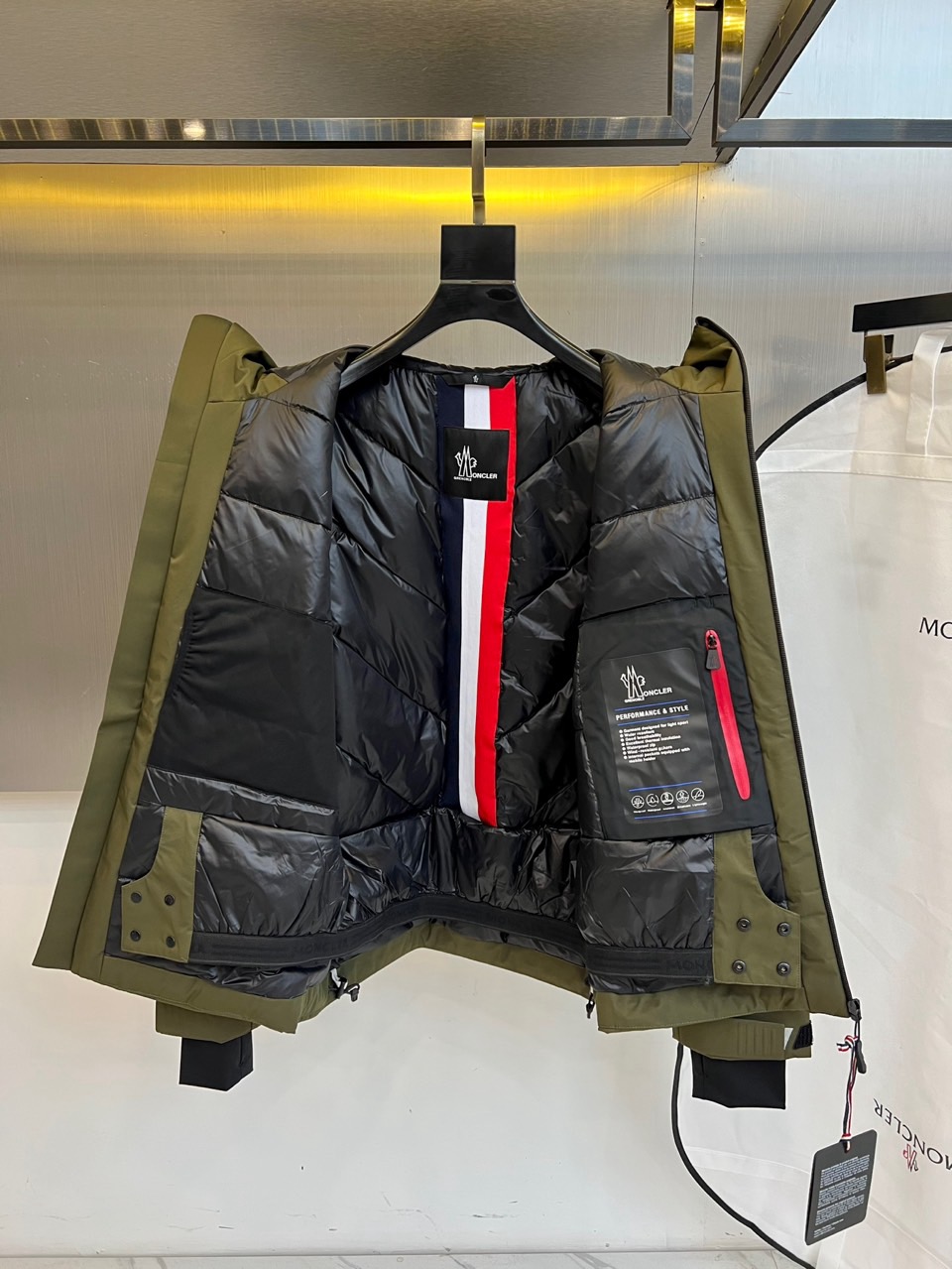 MON蒙口（高端鹅绒）、2025秋冬新品男士连帽羽绒外套，色调演绎现代户外机能风格。连帽设计搭配红白蓝三