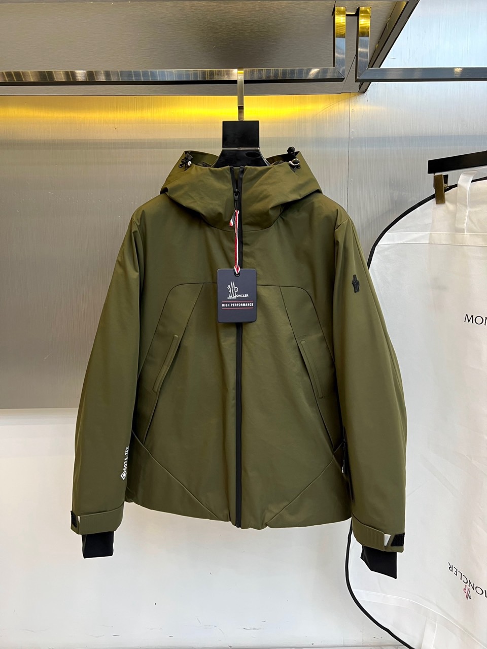 MON蒙口（高端鹅绒）、2025秋冬新品男士连帽羽绒外套，色调演绎现代户外机能风格。连帽设计搭配红白蓝三