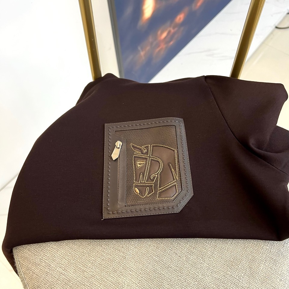 H爱马仕、2025秋冬新品 HERMÈS经典徽章长袖卫衣。这款深紫红色长袖T恤采用品牌标志性圆领设计，左