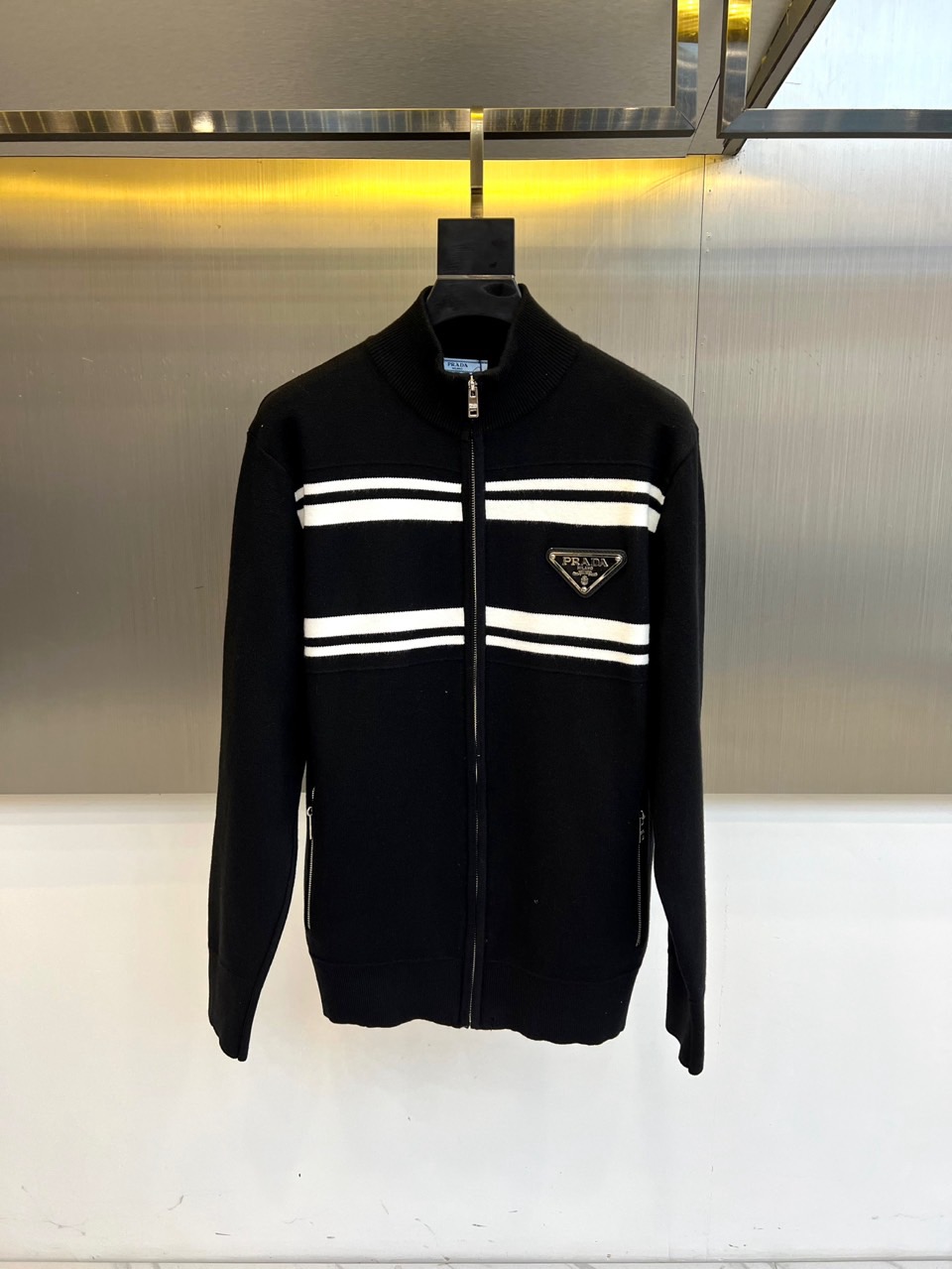 Prad普拉达、2025秋冬新品针织外套，这款外套采用立领设计，搭配顺滑的拉链开合系统，营造利落流畅的线