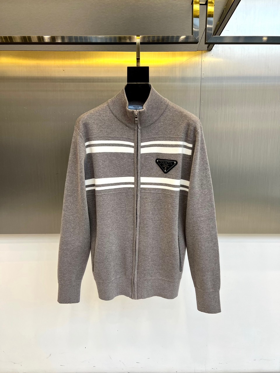 Prad普拉达、2025秋冬新品针织外套，这款外套采用立领设计，搭配顺滑的拉链开合系统，营造利落流畅的线