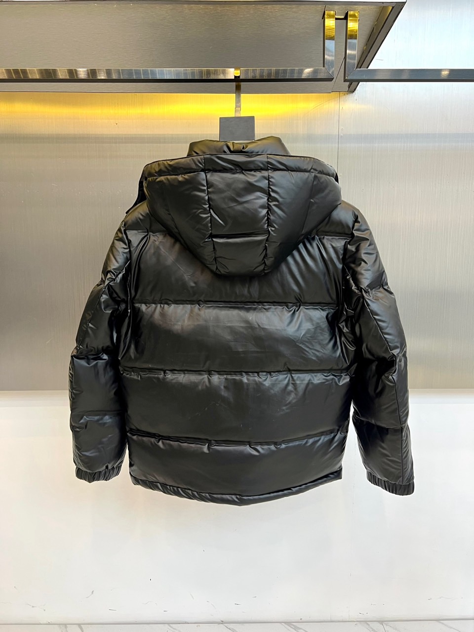 Prad普拉达、2025秋冬新款羽绒服，以纯黑配色演绎意式极简美学。这款连帽羽绒服采用宽松立体剪裁，衣身