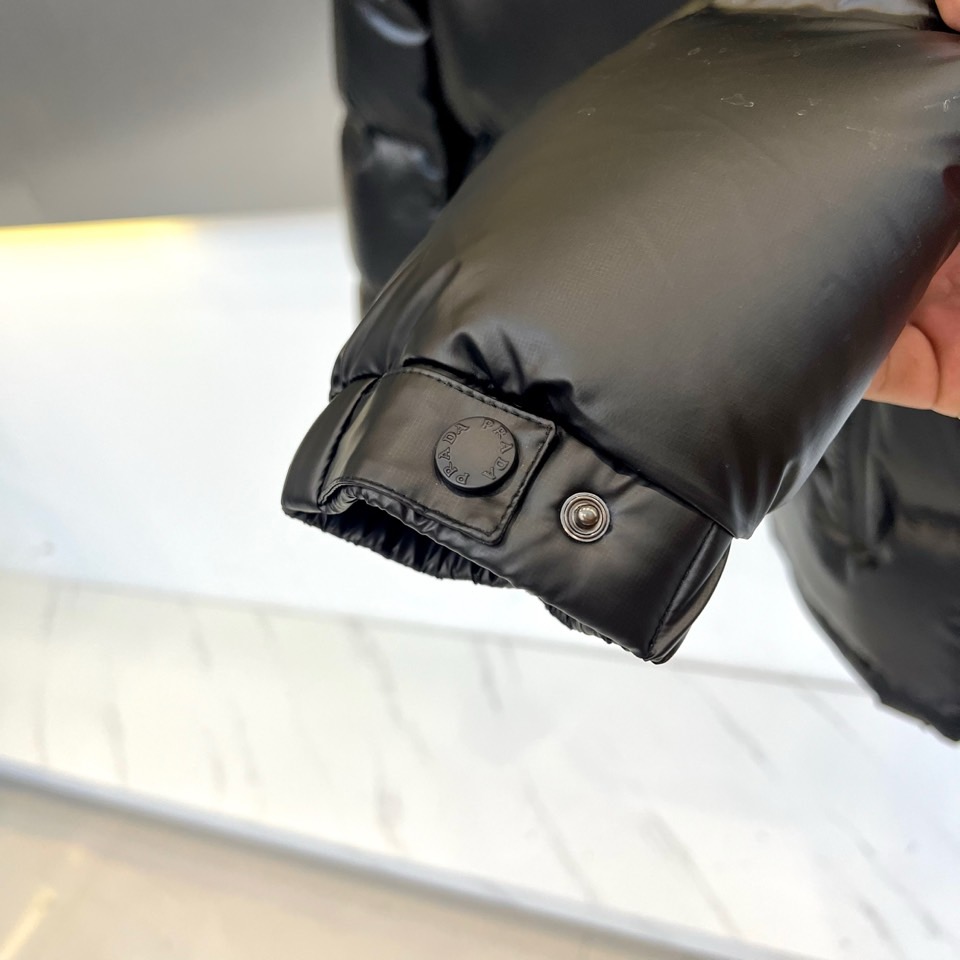 Prad普拉达、2025秋冬新款羽绒服，以纯黑配色演绎意式极简美学。这款连帽羽绒服采用宽松立体剪裁，衣身