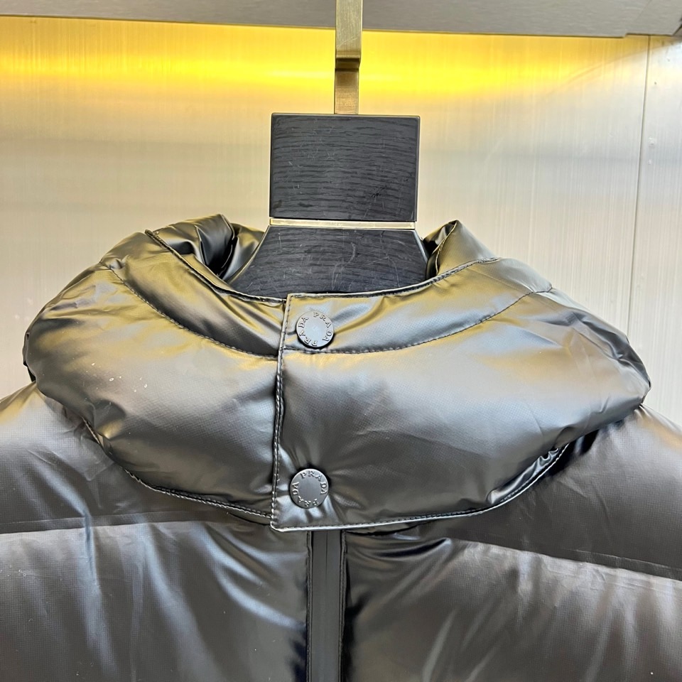 Prad普拉达、2025秋冬新款羽绒服，以纯黑配色演绎意式极简美学。这款连帽羽绒服采用宽松立体剪裁，衣身