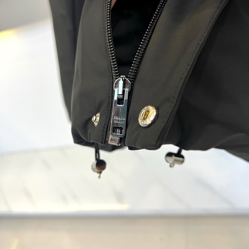 Prad普拉达、2025秋冬新款棉服以深邃藏蓝色演绎都市实用美学。这款连帽棉服采用立体绗缝工艺形成规整的