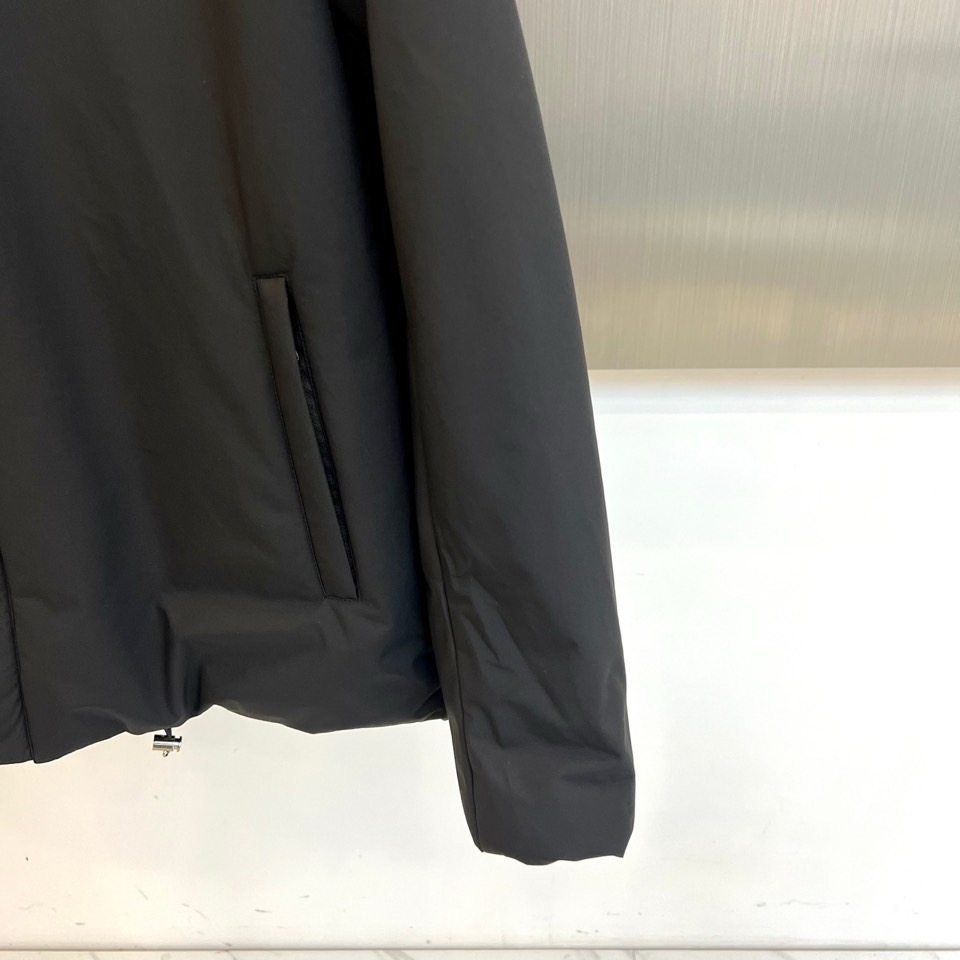 Prad普拉达、2025秋冬新款棉服以深邃藏蓝色演绎都市实用美学。这款连帽棉服采用立体绗缝工艺形成规整的