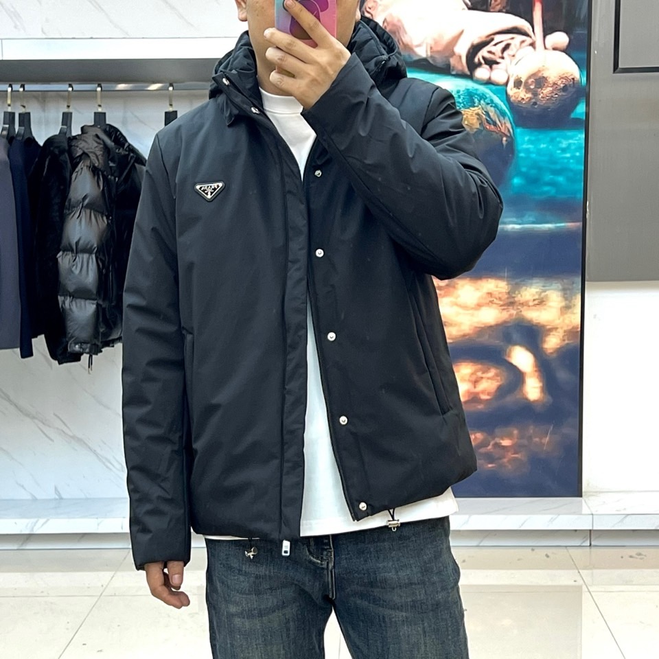 Prad普拉达、2025秋冬新款棉服以深邃藏蓝色演绎都市实用美学。这款连帽棉服采用立体绗缝工艺形成规整的