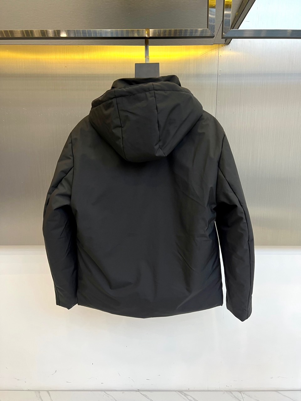 Prad普拉达、2025秋冬新款棉服以深邃藏蓝色演绎都市实用美学。这款连帽棉服采用立体绗缝工艺形成规整的