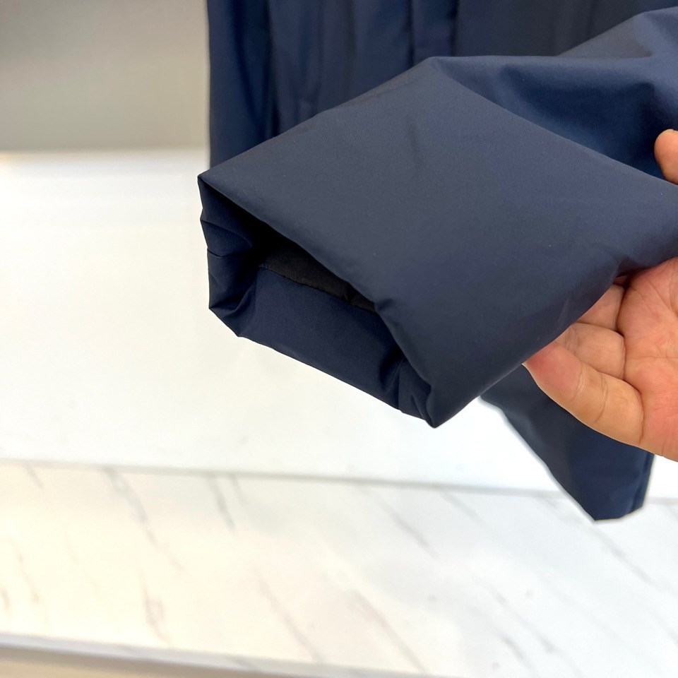 Prad普拉达、2025秋冬新款棉服以深邃藏蓝色演绎都市实用美学。这款连帽棉服采用立体绗缝工艺形成规整的