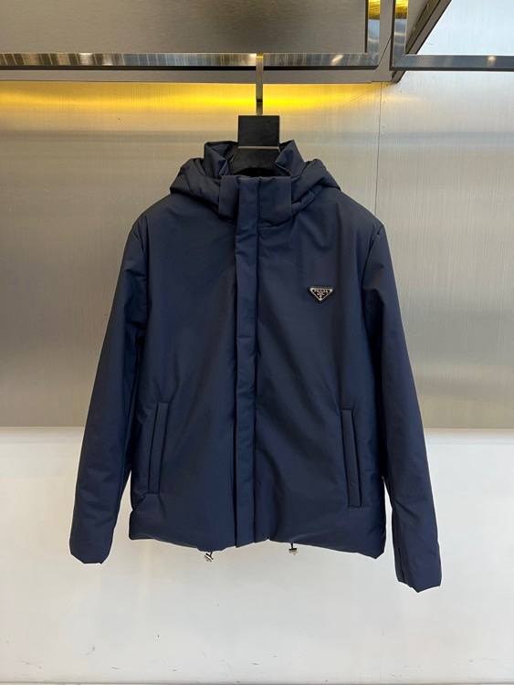 Prad普拉达、2025秋冬新款棉服以深邃藏蓝色演绎都市实用美学。这款连帽棉服采用立体绗缝工艺形成规整的