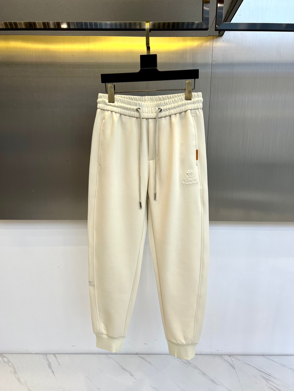 1v威登、2025秋冬新品米白色运动裤，以精湛工艺重新定义休闲奢华。采用顶级斜纹棉质面料，呈现柔和珠光质