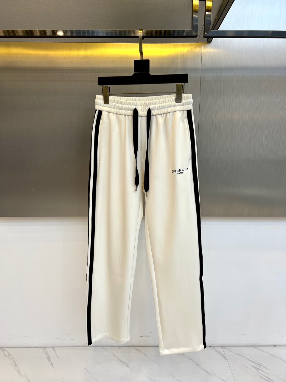 Given纪梵希、2025秋冬新品男士休闲裤，侧边装饰经典黑色条纹，从裤腰延伸至裤脚，形成流畅的视觉线条