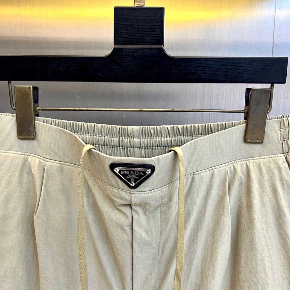 Prad普拉达、2025秋冬新品户外羽绒裤，以浅卡其色演绎山野与都市的跨界美学。这款羽绒裤采用立体剪裁工