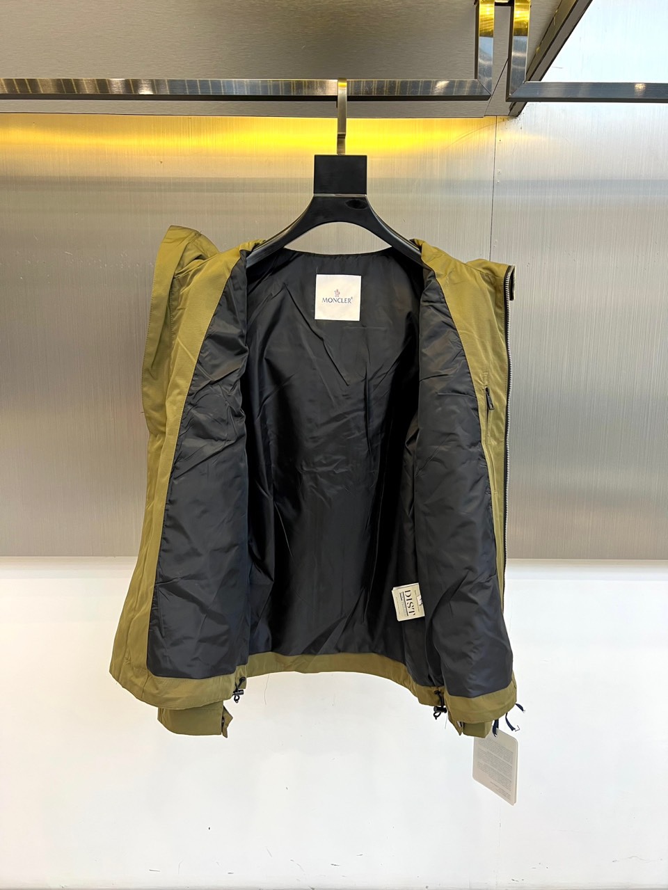 Mon蒙口、2025秋冬新品夹克，这款连帽夹克采用防风面料制作，顺滑的黑色拉链自下摆延伸至立领，左侧帽绳