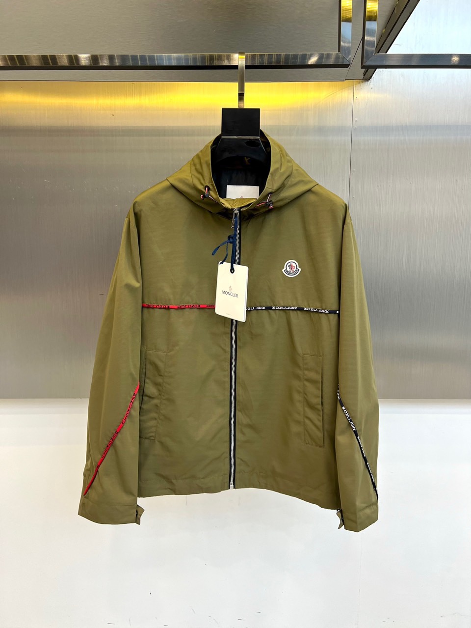 Mon蒙口、2025秋冬新品夹克，这款连帽夹克采用防风面料制作，顺滑的黑色拉链自下摆延伸至立领，左侧帽绳