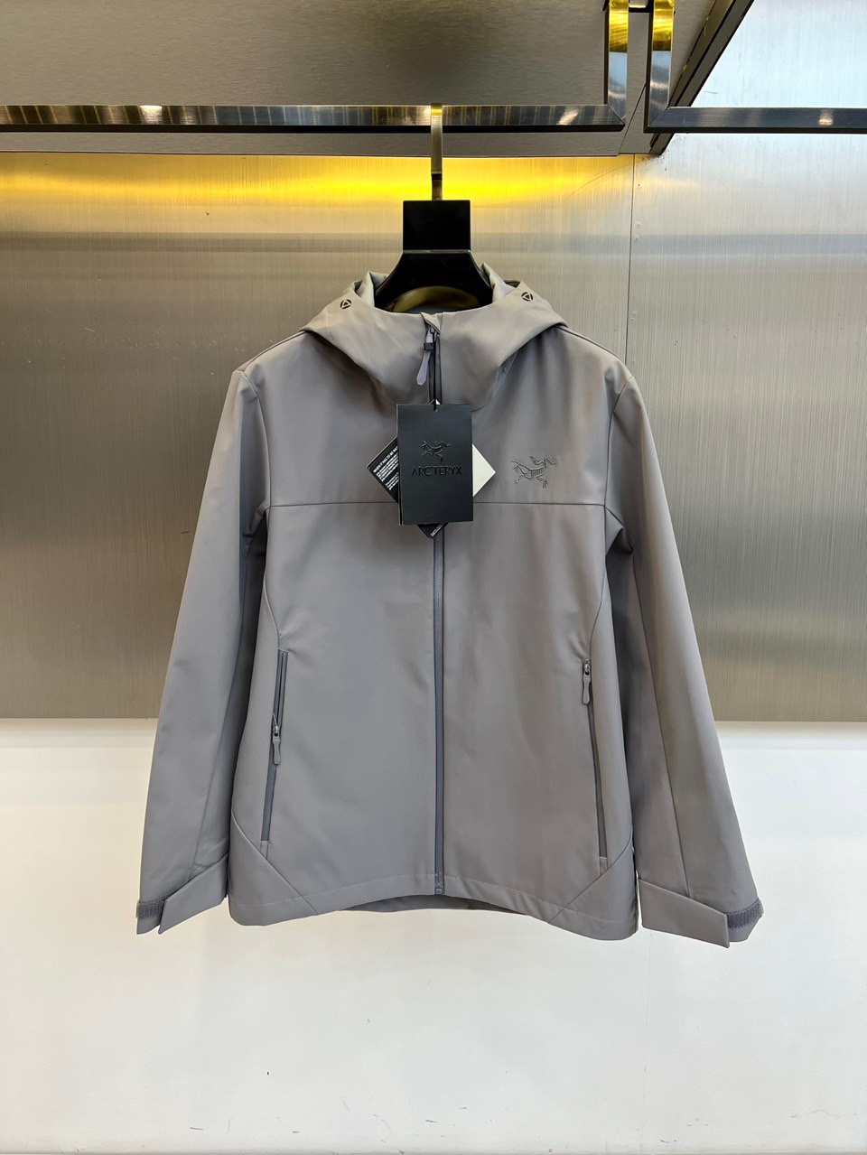 Arcteryx 始祖鸟、2025秋冬新款冲锋衣以浅灰色调诠释专业户外美学。这款连帽冲锋衣采用品牌独家G