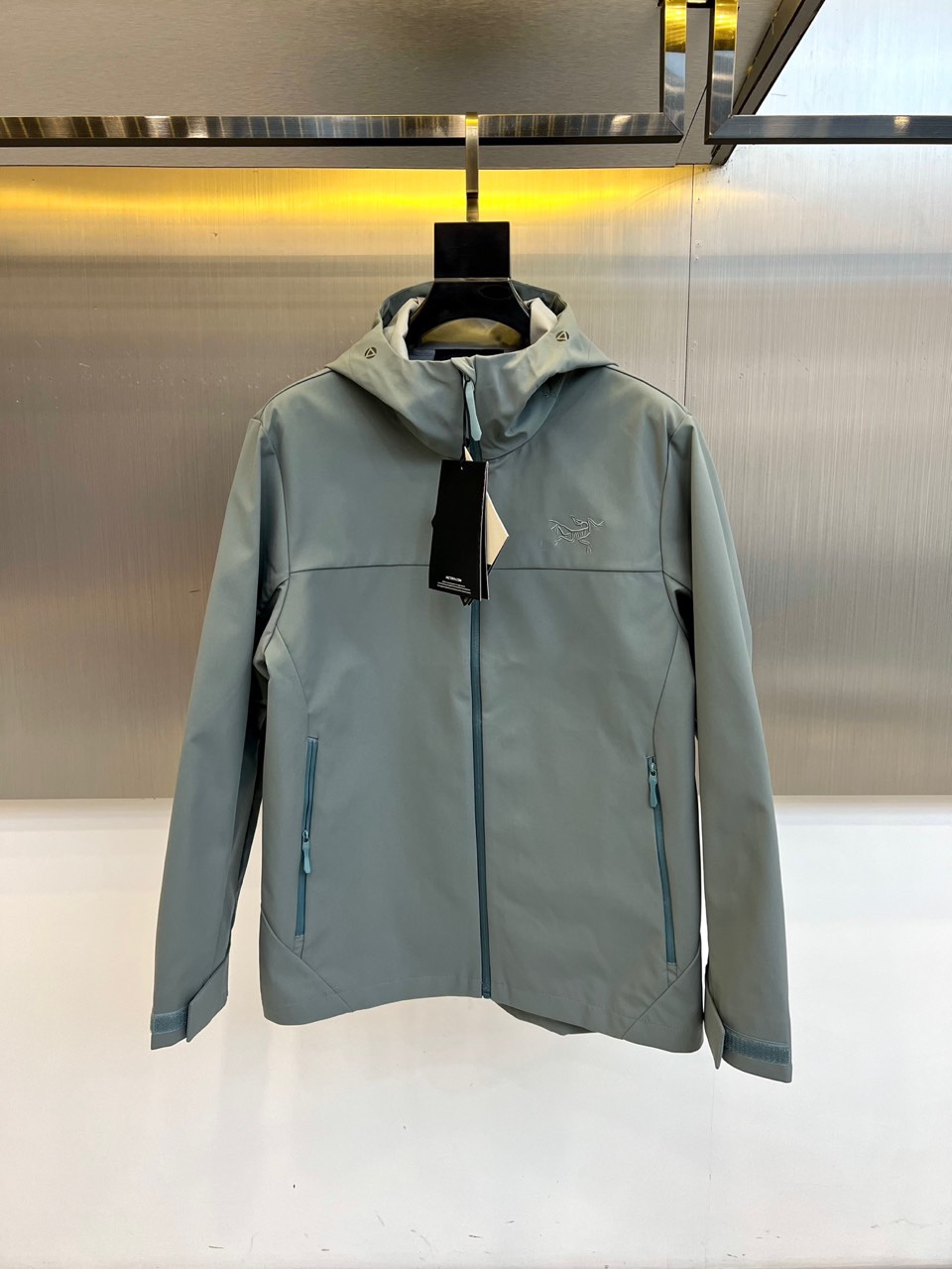 Arcteryx 始祖鸟、2025秋冬新款冲锋衣以浅灰色调诠释专业户外美学。这款连帽冲锋衣采用品牌独家G