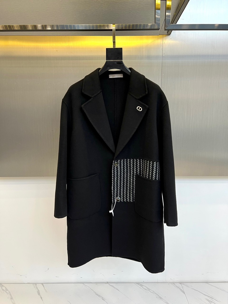 NO:613160,Dio, the new black cashmere coat for autumn and winter 2025, interprets timeless elegance with a classic suit collar design. This coat is made of 68.2 wool and 31.8 polyester fiber blended fabrics, and the lining is polyester fiber, which not only maintains the natural texture of wool, but also adds stiffness to the fabric. The neat straight line tailoring is matched with functional pockets on both sides, and the pockets are cleverly integrated with black and white stripes, injecting modern rhythm into the calm black tone. The upper right side of the collar is embellished with the brand logo, highlighting the low-key luxury brand gene.  Its design perfectly combines French sophistication and pragmatism, and its knee-length length and three-dimensional tailoring create a slender silhouette. Whether it is paired with formal wear to show business temperament, or paired with casual wear to create a daily look, it can naturally show the wearer's fashion taste. From important business occasions to evening social events, this coat can use a simple but not simple design language, becoming a key item to enhance the overall look and texture.  The details reflect Dior's consistent level of craftsmanship, including precise shoulder line processing, even and fine wiring, and metal accessories with outstanding texture. The label clearly indicates the model number 88106 and the grade of qualified products, confirming the brand's strict control of quality. This coat is not only  It is a warm tool and a statement piece that shows the French fashion attitude. It has become an indispensable luxury investment in the autumn and winter wardrobe. 48-56 (model weighs 173,143 pounds and wears a size 50 upper body),, dior, dior, business  suit,alexander wang19860909Dio迪奥、2025秋冬新品黑色羊绒大衣,以经典西装领设计诠释永恒优雅.这款大衣采用68.2羊毛与31.8聚酯纤维混纺面料,里料为聚酯纤维,既保持羊毛的天然质感,又增添面料的挺括度.利落的直线条剪裁配合两侧功能型口袋,口袋处巧妙融入黑白条纹装饰,为沉稳的黑色基调注入现代韵律.领口右上方点缀品牌标志,彰显低调奢华的品牌基因. 其设计将法式精致与实用主义完美融合,过膝长度与立体剪裁营造修长轮廓.无论是搭配正装展现商务气质,还是配合休闲服饰打造日常造型,都能自然展现穿着者的时尚品味.从重要商务场合到晚间社交活动,这件大衣都能以简约而不简单的设计语言,成为提升整体造型质感的关键单品. 细节处体现迪奥一贯的工艺水准精准的肩线处理、均匀细密的走线、质感出众的金属配件.标签明确标注款号88106与合格品等级,印证品牌对品质的严格把控.这件大衣不仅是保暖利器,更是展现法式时尚态度的宣言单品,成为秋冬衣橱中不可或缺的奢华投资.48-56（模特173,143斤上身50码）,,dior,dior,business suit,alexander wang,Men's clothing