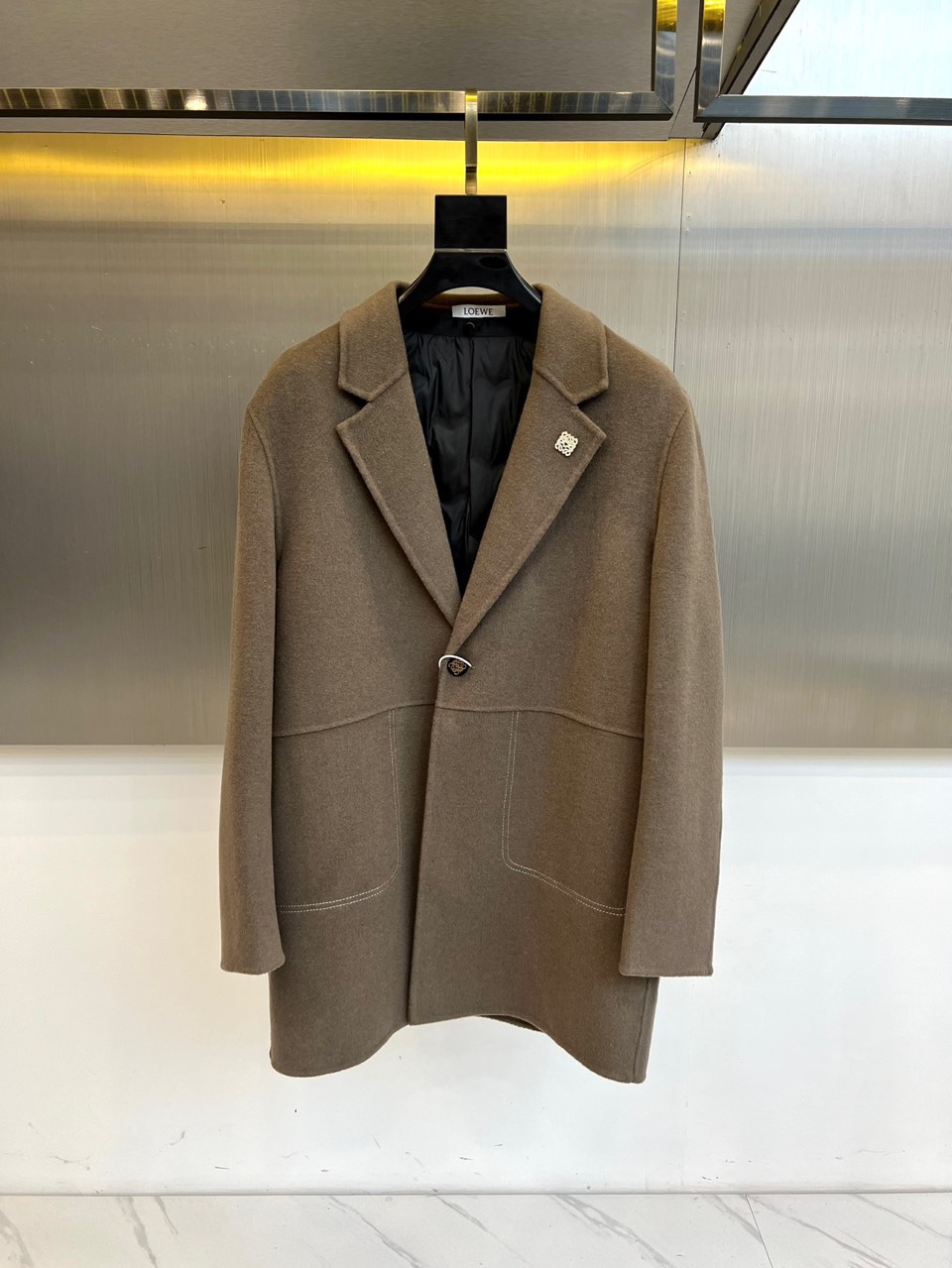 NO:613166,Low Loewe, the new wool coat for autumn and winter 2025. The inner down vest is made of light brown wool blend fabric to demonstrate the style of a modern gentleman. This vest adopts a classic suit collar design with smooth and neat lines, a single metal button embellishes the front, and the brand's iconic emblem is decorated on the left chest. The edges of the symmetrical pockets on both sides are decorated with white lines, forming a subtle contrast with the main body. The interior is filled with black down to ensure light warmth.  The fabric is made of a blend of 68.2 wool and 31.8 polyester fiber, and the lining is polyester fiber, which not only maintains the natural texture of wool, but also adds stiffness to the fabric. Its design perfectly integrates formal elements and practical functions. The light brown tone highlights a warm temperament. It can be paired with a shirt to create a business casual look, or layered under a jacket to enhance the overall sense of hierarchy.  From business meetings to weekend leisure, this vest, with its simple but not simple design language, has become the finishing touch to improve your dressing taste in autumn and winter. The details reflect the brand's craftsmanship, such as precise tailoring and exquisite fabric selection, making the item not only warm and practical, but also an elegant statement showing personal fashion attitude. 48-56 (model 173, 143 pounds, upper body size 50),, loewe, jackets & coats, shirts, down jacket, business suit, alexander  wang19860909Low罗意威、2025秋冬新品羊毛大衣.内里羽绒马甲以浅棕色羊毛混纺面料演绎现代绅士风度.这款马甲采用经典西装领设计,线条流畅利落,单颗金属纽扣点缀前襟,左胸处装饰品牌标志性徽章.两侧对称口袋边缘饰以白色线条,与主体形成微妙对比.内里填充黑色羽绒,确保轻盈保暖性. 面料选用68.2羊毛与31.8聚酯纤维混纺材质,里料为聚酯纤维,既保持羊毛的天然质感,又增添面料的挺括度.其设计将正装元素与实用功能完美融合,浅棕色调彰显温润气质,可搭配衬衫打造商务休闲造型,亦能叠穿在外套内提升整体层次感. 从商务会晤到周末休闲,这件马甲以其简约而不简单的设计语言,成为秋冬季节提升穿搭品味的点睛之笔.细节处体现品牌匠心工艺,如精准的剪裁与考究的面料选择,让单品在保暖实用之余,更成为展现个人时尚态度的优雅宣言.48-56（模特173,143斤上身50码）,,loewe,jackets & coats,shirts,down jacket,business suit,alexander wang,Men's clothing