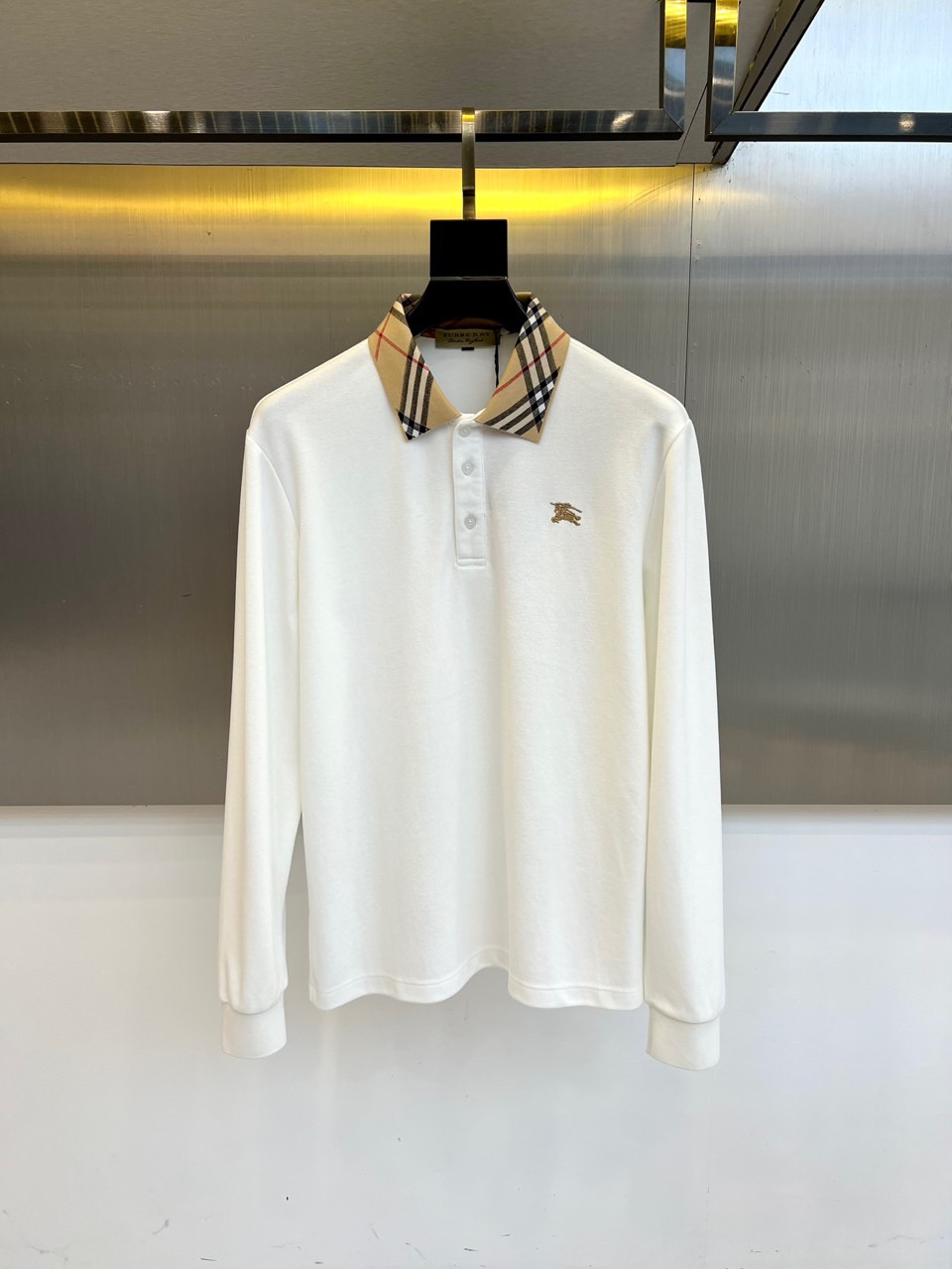 NO:613195,Burberry, the new men's long-sleeved Polo shirt for autumn and winter 2025, this Polo shirt adopts a classic lapel design, and the collar is paved with the brand's iconic brown and black black plaid, which forms a delicate contrast with the simple body. The left chest is embellished with a golden pony embroidery badge, using three-dimensional stitching to outline the century-old brand genes. The fabric is made of a blend of 69.1 cotton and 30.9 polyester fiber, which not only retains the skin-friendly breathability of pure cotton, but also has the stiffness and shape-retaining advantages of polyester fiber.  Its tailoring follows a modern slim fit, and the ratio of sleeve length to hem has been precisely calculated. It complies with GB/T22849-executive standards and GB18401-2010 Class B safety regulations for direct contact with skin, ensuring wearing comfort and quality reliability. The inside of the plaid collar uses the same color hemming process, and the details show ingenuity.  This Polo shirt perfectly balances business casual and daily fashion. It can be paired with chinos to show a gentleman's style, or it can be combined with jeans to create an urban style. From weekend golf courses to business meetings, the wearer can naturally reveal a low-key and luxurious British temperament. The combination of classic plaid and gold badges  Together, it continues Burberry's modern expression of traditional elements and has become a must-have item in the autumn and winter wardrobe that is both practical and brand-recognizable. 48-56 (model weighs 173,143 pounds, upper body size 50),,burberry,burberry,jeans,alexander  wang19860909Bur巴宝莉、2025秋冬新品男士长袖Polo衫,这款Polo衫采用经典翻领设计,领面铺陈品牌标志性棕黑白三色格纹,与简约衣身形成精致对比.左胸处点缀金色小马刺绣徽章,以立体针法勾勒百年品牌基因.面料选用69.1棉与30.9聚酯纤维混纺材质,既保留纯棉的亲肤透气性,又兼具聚酯纤维的挺括保形优势. 其剪裁遵循现代修身版型,袖长与衣摆比例经过精密计算.符合GB/T22849-执行标准与GB18401-2010 B类直接接触皮肤安全规范,确保穿着舒适度与品质可靠性.格纹领口内侧采用同色系包边工艺,细节处展现匠心制作. 这款Polo衫将商务休闲与日常时尚完美平衡,既可搭配斜纹裤展现绅士风度,也能与牛仔裤组合打造都市型格.从周末高尔夫球场到商务会晤场合,都能让穿着者自然流露低调奢华的英伦气质.经典格纹与金色徽章的组合,延续巴宝莉对传统元素的现代表达,成为秋冬衣橱中兼具实穿性与品牌辨识度的必备单品.48-56（模特173,143斤上身50码）,,burberry,burberry,jeans,alexander wang,Men's clothing