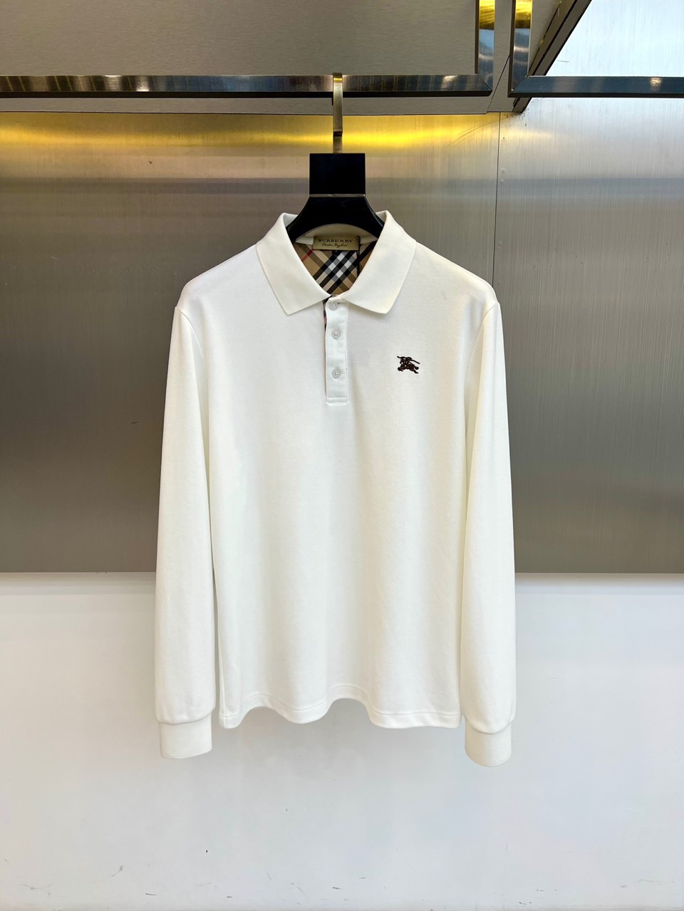 NO:613143,Burberry, new men's Polo shirt for autumn and winter 2025, this long-sleeved Polo shirt adopts a classic lapel design, equipped with three white buttons on the collar, and is embellished with the brand's iconic black pony embroidery badge on the left chest, highlighting the century-old brand genes. The classic plaid lining is hidden on the inside of the collar, and the beige, black and brown plaid patterns interweave to reveal a luxurious texture from the details.  The fabric uses a golden ratio of 69.1 cotton and 30.9 polyester fiber, which not only maintains the skin-friendly breathability of pure cotton, but also incorporates the stiffness and shape-retaining advantages of polyester fiber. The slim fit is combined with smooth body lines, and the ratio of sleeve length to hem is precisely calculated. It complies with GB18401-2010 Class B safety standards for direct contact with skin to ensure wearing comfort.  Its design perfectly balances casualness and formality. It can be paired with trousers to create a business casual look, or it can be combined with jeans for daily fashion. From golf courses to urban clubs, this Polo shirt can allow the wearer to naturally show a low-key aristocratic temperament. Details such as the collar plaid and embroidered badges continue to  Burberry's insistence on traditional craftsmanship has become a must-have item that is both practical and brand-recognizable in autumn and winter. 48-56 (173,143 pounds in a certain place, upper body size 50),,burberry,burberry,jeans,gold,alexander  wang19860909Bur巴宝莉、2025秋冬新品男士Polo衫,这款长袖Polo衫采用经典翻领设计,领口配有三颗白色纽扣,左胸处点缀品牌标志性黑色小马刺绣徽章,彰显百年品牌基因.领口内侧暗藏经典格纹内衬,米色、黑色与棕色交织的格纹图案从细节流露奢华质感. 面料选用69.1棉与30.9聚酯纤维的黄金配比,既保持纯棉材质的亲肤透气性,又融入聚酯纤维的挺括保形优势.修身剪裁配合流畅的衣身线条,袖长与衣摆比例经过精密计算.符合GB18401-2010 B类直接接触皮肤安全标准,确保穿着舒适度. 其设计将休闲与正式完美平衡,既可搭配西裤打造商务休闲造型,也能与牛仔裤组合呈现日常时尚.从高尔夫球场到都市会所,这件Polo衫都能让穿着者自然展现低调的贵族气质.领口格纹与刺绣徽章等细节,延续巴宝莉对传统工艺的坚持,成为秋冬季节兼具实穿性与品牌辨识度的必备单品.48-56（某地173,143斤上身50码）,,burberry,burberry,jeans,gold,alexander wang,Men's clothing