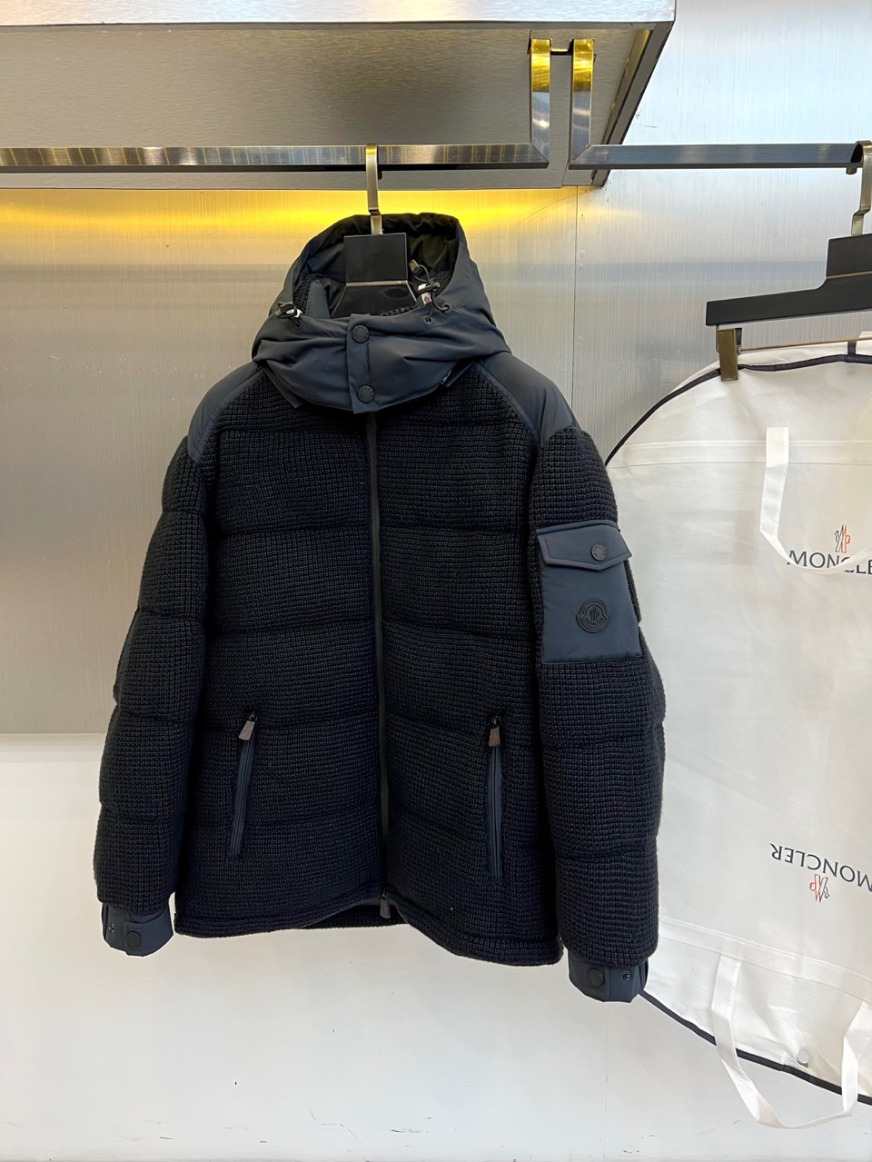 NO:613155,Mon (white goose down), the new black down jacket for autumn and winter 2025, interprets winter luxury aesthetics with a simple design. The style adopts a hooded design with smooth zipper closure. The body is covered with exquisite plaid quilting texture. The left arm is equipped with practical patch pockets and is embellished with brand logos.  Shi. The fabric is made of high-tech windproof material, filled with a combination of 90% pure goose down and 10% feathers. It strictly follows the EU EN12934 and the United States USA-standard certification. The style perfectly combines outdoor functions and urban fashion, and the main tone of black highlights eternal elegance.  The plaid texture adds layering to the simple design. This down jacket can not only withstand the cold weather, but also maintains a fashionable silhouette through neat tailoring. Whether it is paired with casual trousers to create a daily look, or paired with functional clothing for outdoor scenes, it can show its quality.  The dual pursuit of aesthetics. From the precise quilting process to the iconic badge details, they all reflect the brand's ingenious spirit, making winter wear warm and stylish. Sizes 1-5 (model 173, 143 pounds upper body size 2), Moncler, down  jacket,hats,alexander wang19860909Mon蒙口（白鹅绒）、2025秋冬新品黑色羽绒服,以简约设计演绎冬日奢华美学.款式采用连帽设计搭配顺滑拉链开合,衣身布满精致的格纹绗缝纹理,左臂设实用贴袋并点缀品牌标识.面料选用高科技防风材质,填充90纯净鹅绒与10羽毛组合,严格遵循欧盟EN12934与美国USA-标准认证.风格上完美融合户外机能与都市时尚,黑色主调彰显永恒优雅,格纹肌理为简约设计增添层次感.这款羽绒服既能抵御严寒气候,又通过利落剪裁保持时尚轮廓,无论是搭配休闲裤装打造日常造型,还是配合功能服饰应对户外场景,都能展现蒙口对品质与美学的双重追求.从精准的绗缝工艺到标志性徽章细节,皆体现品牌匠心精神,让冬日穿着既温暖又不失型格.1-5码（模特173,143斤上身2码）,,Moncler,down jacket,hats,alexander wang,Men's clothing