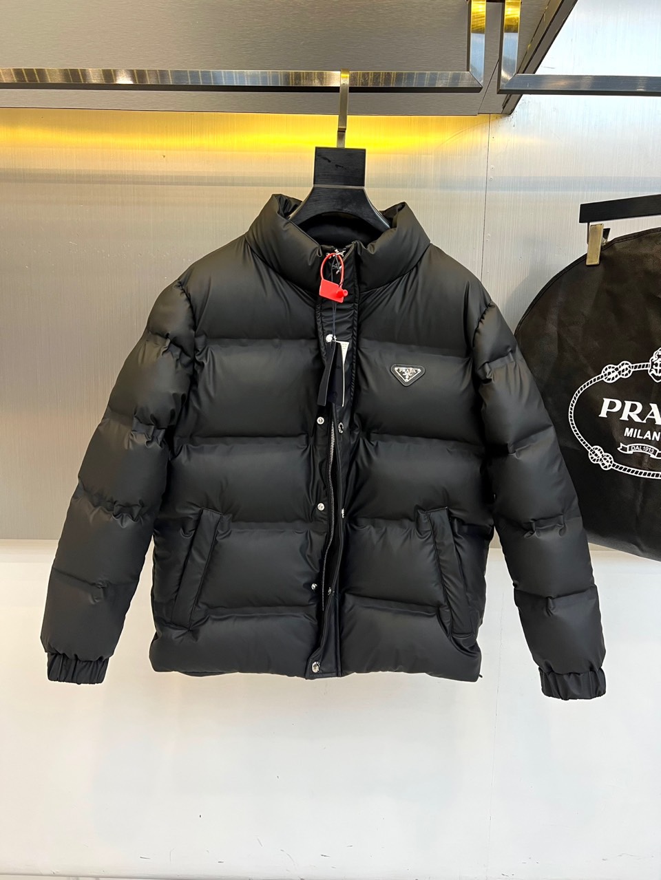 NO:613191,Prad, the new 2025 autumn and winter down jacket, interprets Italian luxury aesthetics in classic black. This down jacket has a stand-up collar design, the front is equipped with a double closure system of metal buttons and zippers, and the brand's iconic triangle logo is embellished on the left chest to highlight its identity. The diagonal pockets on both sides combine practical functions and smooth lines, and the cuffs and hems are designed with elastic edges to enhance warmth. The fabric is filled with a golden ratio of 90% high-quality down and 10% feathers to ensure a light texture and excellent thermal performance. Its design will be practical  The fusion of doctrine and high fashion language, three-dimensional tailoring avoids bulkiness, and smooth fabrics present a low-key luster. From urban commuting to winter travel, this down jacket has Prada's unique minimalist aesthetics and exquisite craftsmanship, becoming a winter must-have for those who pursue quality life. The multi-language ingredient labeling on the label reflects the brand's rigorous attention to details, and professional washing icons guide caring care methods. 48-56 (model 173, 143 pounds, upper body size 50),, prada, prada, down  jacket,gold,alexander wang19860909Prad普拉、2025秋冬新款羽绒服,以经典黑色演绎意式奢华美学.这款羽绒服采用立领设计,前襟配备金属纽扣与拉链双重闭合系统,左胸点缀品牌标志性三角徽标彰显身份.两侧斜插口袋兼顾实用功能与流畅线条,袖口与下摆采用弹性收边设计增强保暖性.面料填充90优质羽绒与10羽毛的黄金配比,确保轻盈质感与卓越保暖性能.其设计将实用主义与高级时装语言相融合,立体剪裁避免臃肿感,光滑面料呈现低调光泽.从都市通勤到冬季旅行,这件羽绒服以普拉达特有的极简美学与精湛工艺,成为追求品质生活人士的冬日必备.标签处多国语言成分标注体现品牌对细节的严谨,专业洗涤图标指引贴心护理方式.48-56（模特173,143斤上身50码）,,prada,prada,down jacket,gold,alexander wang,Men's clothing