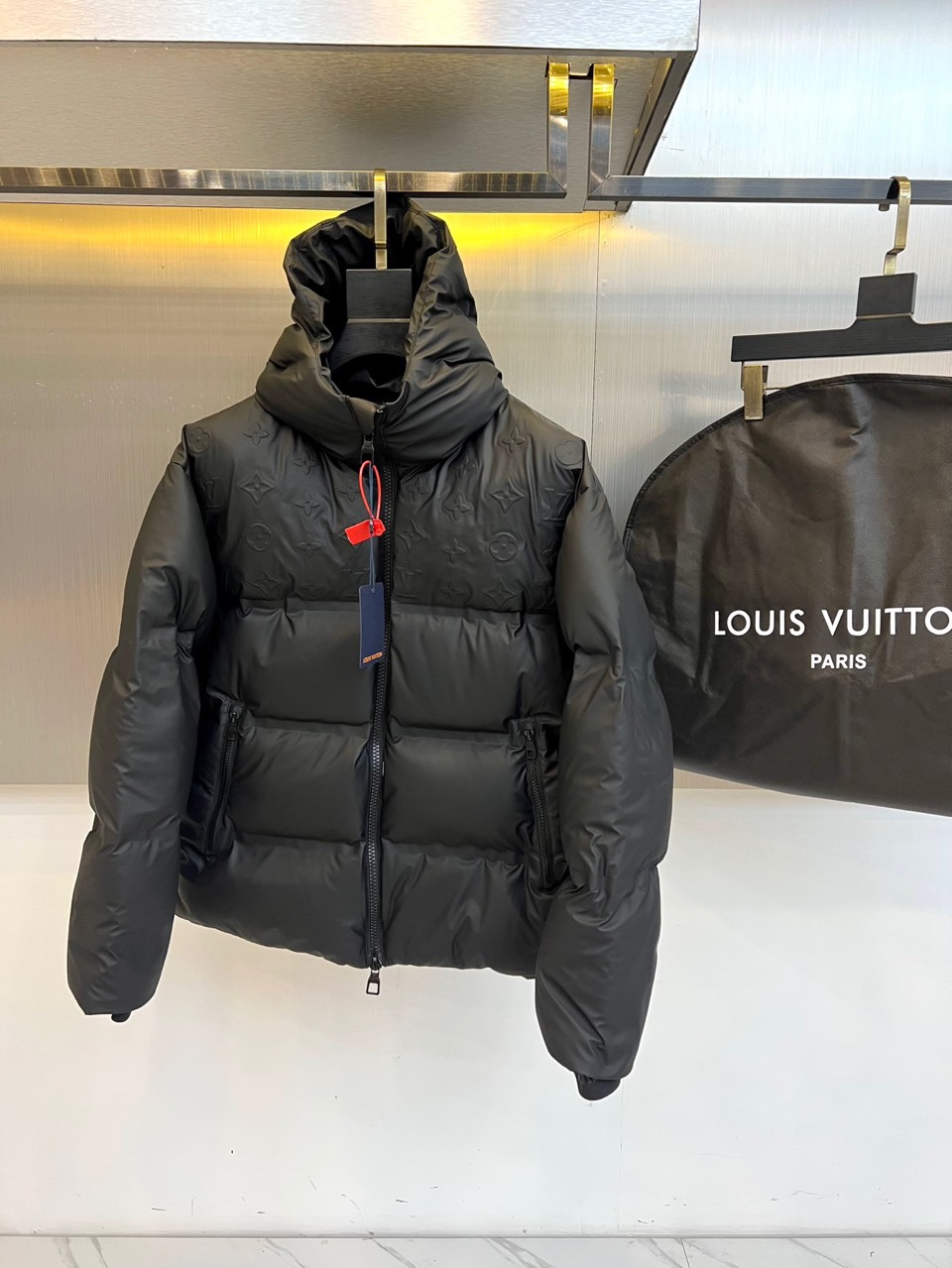 NO:613196,1v Vuitton (goose down), the new 2025 autumn and winter down jacket uses classic black to interpret luxurious and functional aesthetics. This hooded down jacket is made of the brand's iconic Monogram presbyopic dark pattern fabric, and the delicate printed pattern is faintly visible on the black background, highlighting the low-key luxury brand gene. The front is equipped with a smooth zipper opening and closing system, and the adjustable hood design enhances practical performance. The diagonal pockets on both sides combine storage function and smooth lines, and the red and blue color tag at the collar is the finishing touch.  The fabric is filled with a golden ratio of 90 down and 10 feathers to ensure excellent thermal performance and light texture. Its design perfectly blends outdoor functionality with urban fashion. The three-dimensional tailoring avoids the bloated feeling of traditional down jackets, and the presbyopic pattern gives the item unique recognition. From urban commuting to weekend trips, this down jacket can be paired with formal wear to show a business casual style, or combined with sportswear to create a trendy look.  Details reflect Louis Vuitton's exquisite craftsmanship, precise stitching, smooth zipper experience, and a bonus dust bag from the same series. Every design highlights the brand's insistence on quality, making this down jacket a must-have for the autumn and winter wardrobes of elites who pursue both fashion and functionality. 48-56 (model 173,143 pounds, upper body size 50),, louis vuitton, down jacket, gold, hats, alexander wang198609091v威登（鹅绒）、2025秋冬新款羽绒服以经典黑色演绎奢华机能美学.这款连帽羽绒服采用品牌标志性Monogram老花暗纹面料,细腻的印花图案在黑色背景下若隐若现,彰显低调奢华的品牌基因.前襟配备顺滑拉链开合系统,可调节连帽设计增强实用性能.两侧斜插口袋兼顾储物功能与线条流畅感,领口处的红蓝配色吊牌成为点睛之笔. 面料采用90羽绒与10羽毛的黄金配比填充,确保卓越的保暖性能与轻盈质感.其设计将户外功能性与都市时尚感完美融合,立体剪裁避免传统羽绒服的臃肿感,老花图案赋予单品独特的辨识度.从城市通勤到周末出行,这件羽绒服既能搭配正装展现商务休闲风格,也可结合运动服饰打造潮流造型. 细节处体现路易威登的精湛工艺精准的缝线走位、顺滑的拉链体验、附赠的同系列防尘袋.每处设计都彰显品牌对品质的坚持,使这款羽绒服成为追求时尚与功能兼具的精英人士秋冬衣橱的必备之选.48-56（模特173,143斤上身50码）,,louis vuitton,down jacket,gold,hats,alexander wang,Men's clothing