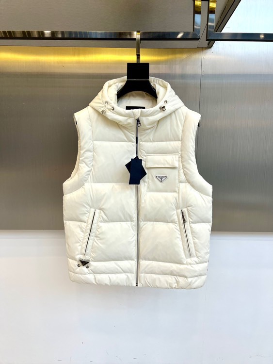 NO:613150,Prad, 2025 autumn and winter new down vest, this hooded vest is slim fit, equipped with a smooth zipper closure system on the front, and the left chest pocket is decorated with a classic triangular enamel logo. Practical zipper pockets on both sides are both functional and smooth.  Line, adjustable drawstring hood enhances windproof performance. The fabric is made of 82.1 nylon and 17.9 spandex blended material to ensure a light texture and moderate elasticity, and is lined with high-quality down to provide warmth. Its design combines practical function with Italian elegance  Perfectly integrated, the white tone highlights a fresh temperament, and the neat silhouette is suitable for a variety of inner wear. From urban commuting to weekend leisure, this vest can be worn with a knitted sweater to create a layered look, or layered under a jacket to increase warmth. The precise routing and quality in the details  The brand logo shows Prada's insistence on craftsmanship and has become a must-have item that is both practical and fashionable in autumn and winter. 48-56 (model weighs 173,143 pounds and upper body is size 50),, prada, prada, jackets  & coats,down jacket,hats,alexander wang19860909Prad普拉达、2025秋冬新品羽绒马甲,这款连帽马甲采用修身剪裁,前襟配备顺滑拉链开合系统,左侧胸袋装饰经典三角形珐琅徽标.两侧实用拉链口袋兼顾功能性与流畅线条,可调节抽绳连帽增强防风性能.面料选用82.1锦纶与17.9氨纶混纺材质,确保轻盈质感与适度弹性,内衬填充优质羽绒提供保暖保障.其设计将实用功能与意式优雅完美融合,白色调彰显清新气质,利落版型适配多种内搭.从都市通勤到周末休闲,这件马甲既能搭配针织衫打造层次造型,也可叠穿在外套内提升保暖度.细节处的精准走线与品牌标识,展现普拉达对工艺的坚持,成为秋冬季节兼具实穿性与时尚感的必备单品.48-56（模特173,143斤上身50码）,,prada,prada,jackets & coats,down jacket,hats,alexander wang,Men's clothing