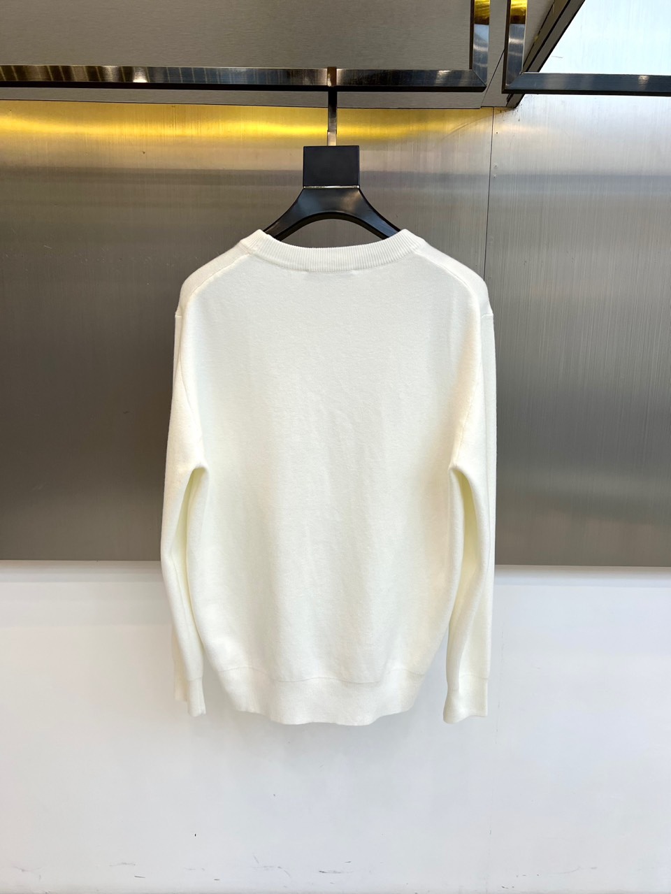 Prad普拉、2025秋冬新品白色针织毛衣，以极简主义美学诠释当代优雅。这款毛衣采用经典圆领设计，左胸位