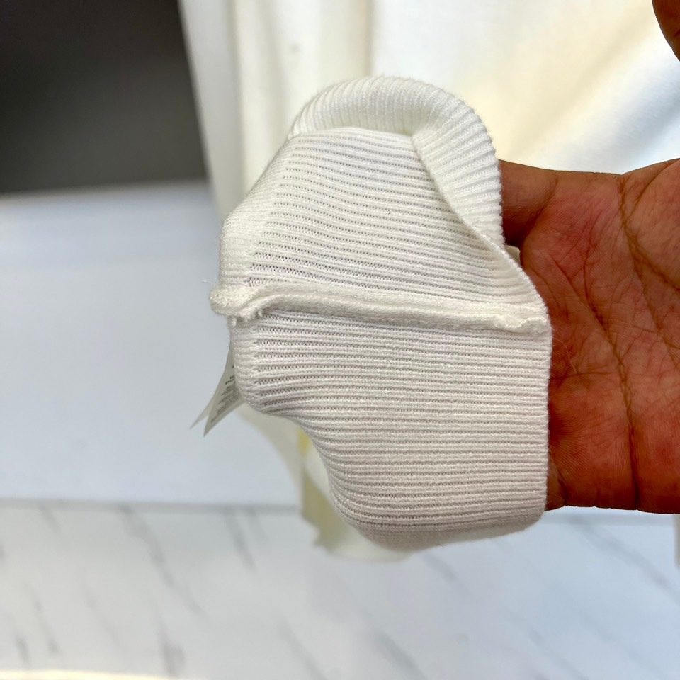 Prad普拉、2025秋冬新品白色针织毛衣，以极简主义美学诠释当代优雅。这款毛衣采用经典圆领设计，左胸位