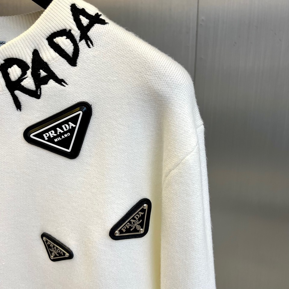 Prad普拉、2025秋冬新品白色针织毛衣，以极简主义美学诠释当代优雅。这款毛衣采用经典圆领设计，左胸位