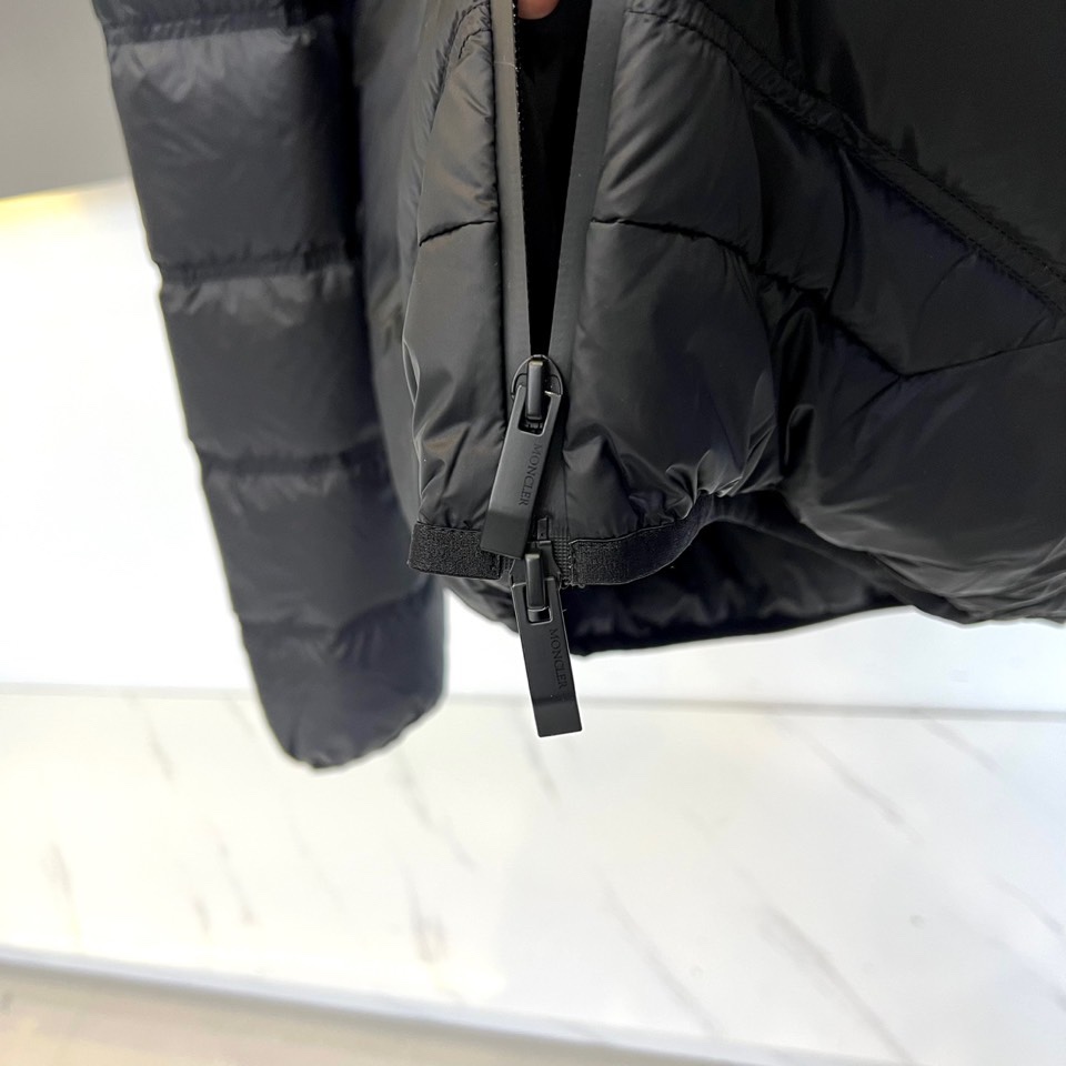 Mon蒙口（纯鹅绒）、2025秋冬新款羽绒服，以经典黑色演绎都市户外美学。这款连帽羽绒服采用横向绗缝工艺