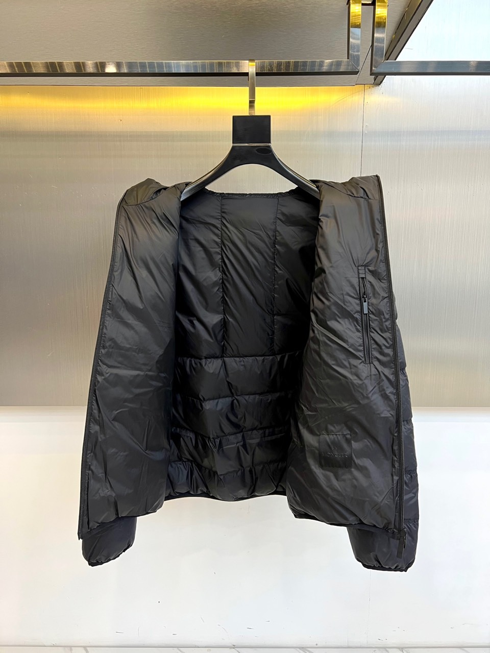 Mon蒙口（纯鹅绒）、2025秋冬新款羽绒服，以经典黑色演绎都市户外美学。这款连帽羽绒服采用横向绗缝工艺