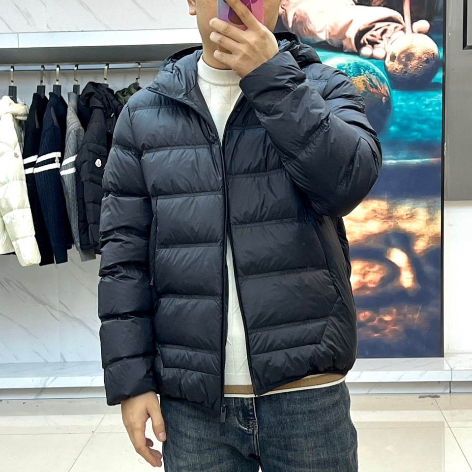 Mon蒙口（纯鹅绒）、2025秋冬新款羽绒服，以经典黑色演绎都市户外美学。这款连帽羽绒服采用横向绗缝工艺