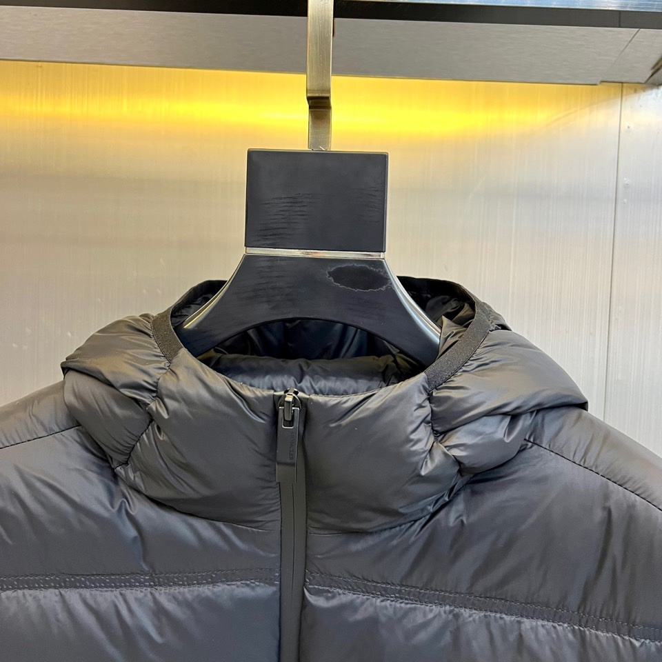 Mon蒙口（纯鹅绒）、2025秋冬新款羽绒服，以经典黑色演绎都市户外美学。这款连帽羽绒服采用横向绗缝工艺