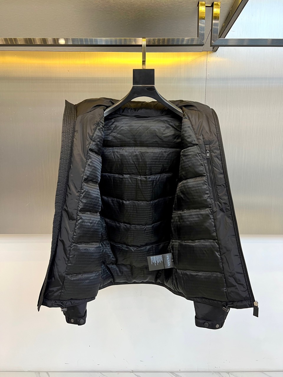 \nPrad普拉达、2025秋冬新款羽绒服，以经典黑色演绎意式极简美学。这款连帽羽绒服采用立体菱形绗缝工