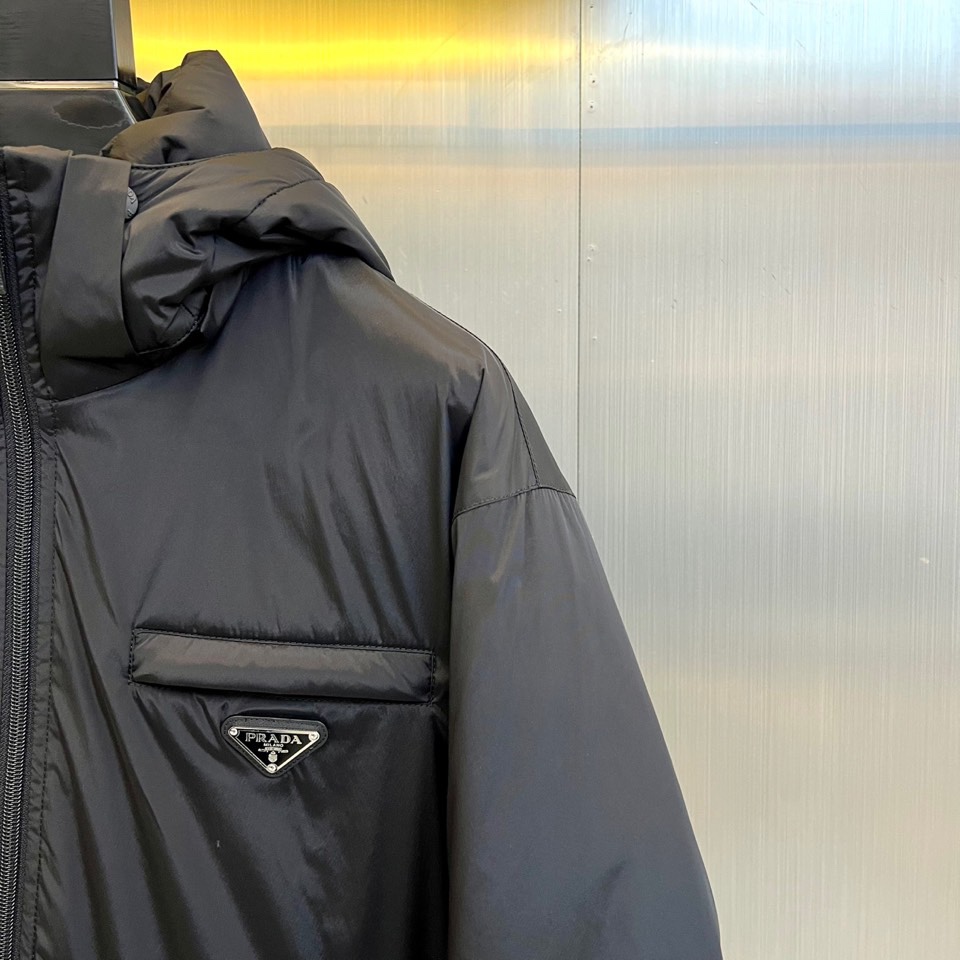 \nPrad普拉达、2025秋冬新款羽绒服，以经典黑色演绎意式极简美学。这款连帽羽绒服采用立体菱形绗缝工