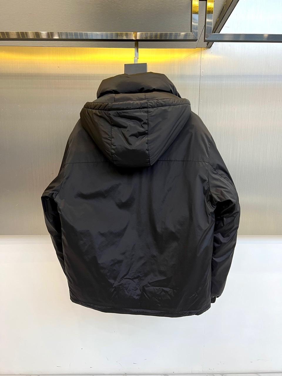 \nPrad普拉达、2025秋冬新款羽绒服，以经典黑色演绎意式极简美学。这款连帽羽绒服采用立体菱形绗缝工