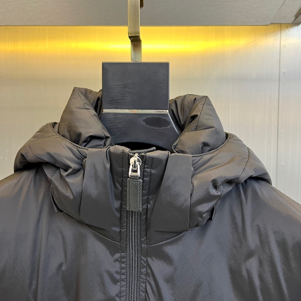 \nPrad普拉达、2025秋冬新款羽绒服，以经典黑色演绎意式极简美学。这款连帽羽绒服采用立体菱形绗缝工