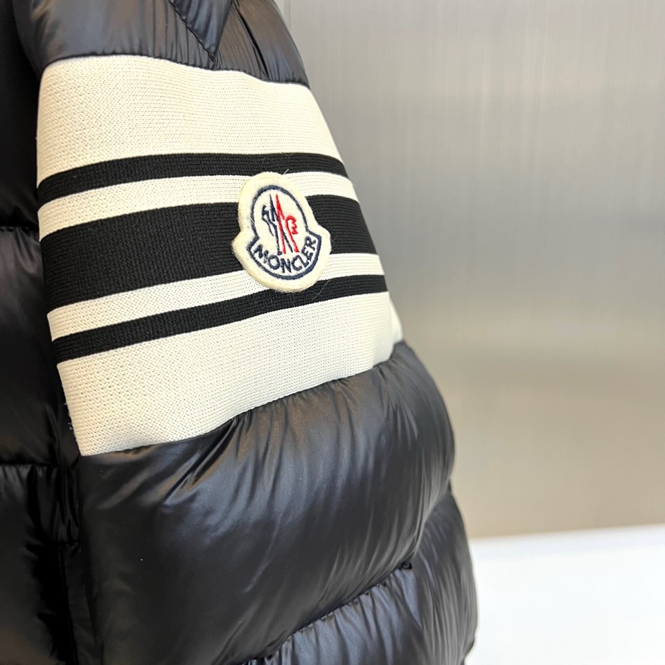 Mon蒙口、2025秋冬新品羽绒服，连帽设计搭配顺滑拉链开合，左臂饰有品牌标志性黑白条纹织带与浮雕徽章，