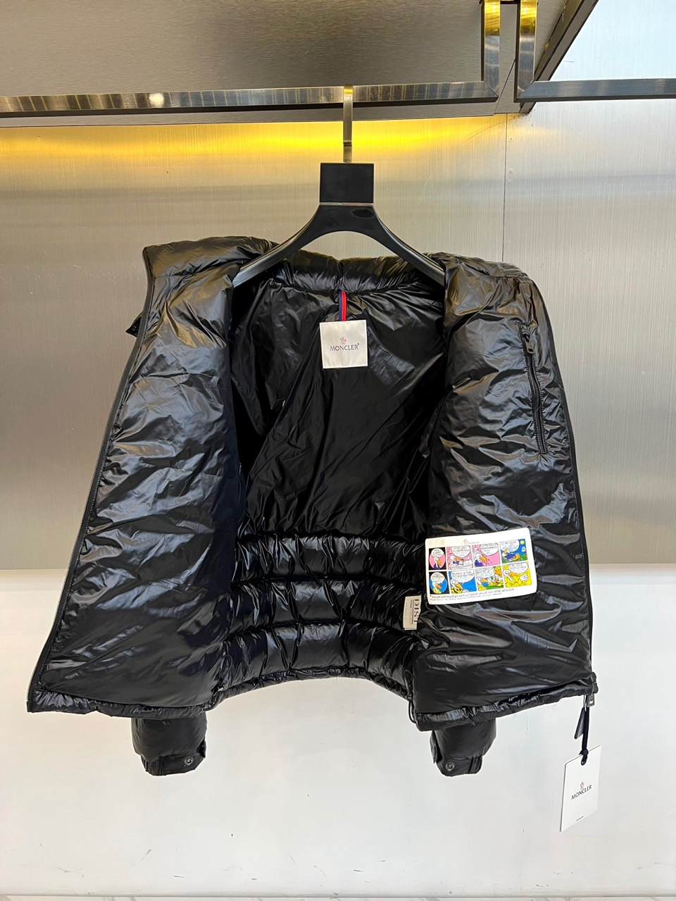 Mon蒙口、2025秋冬新品羽绒服，连帽设计搭配顺滑拉链开合，左臂饰有品牌标志性黑白条纹织带与浮雕徽章，